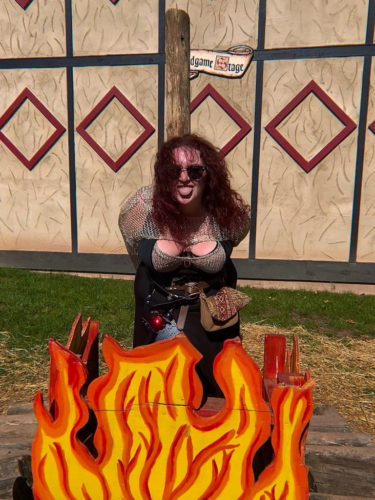 Lis sticking their tongue out being burned at a fake wooden stake at a renn faire 