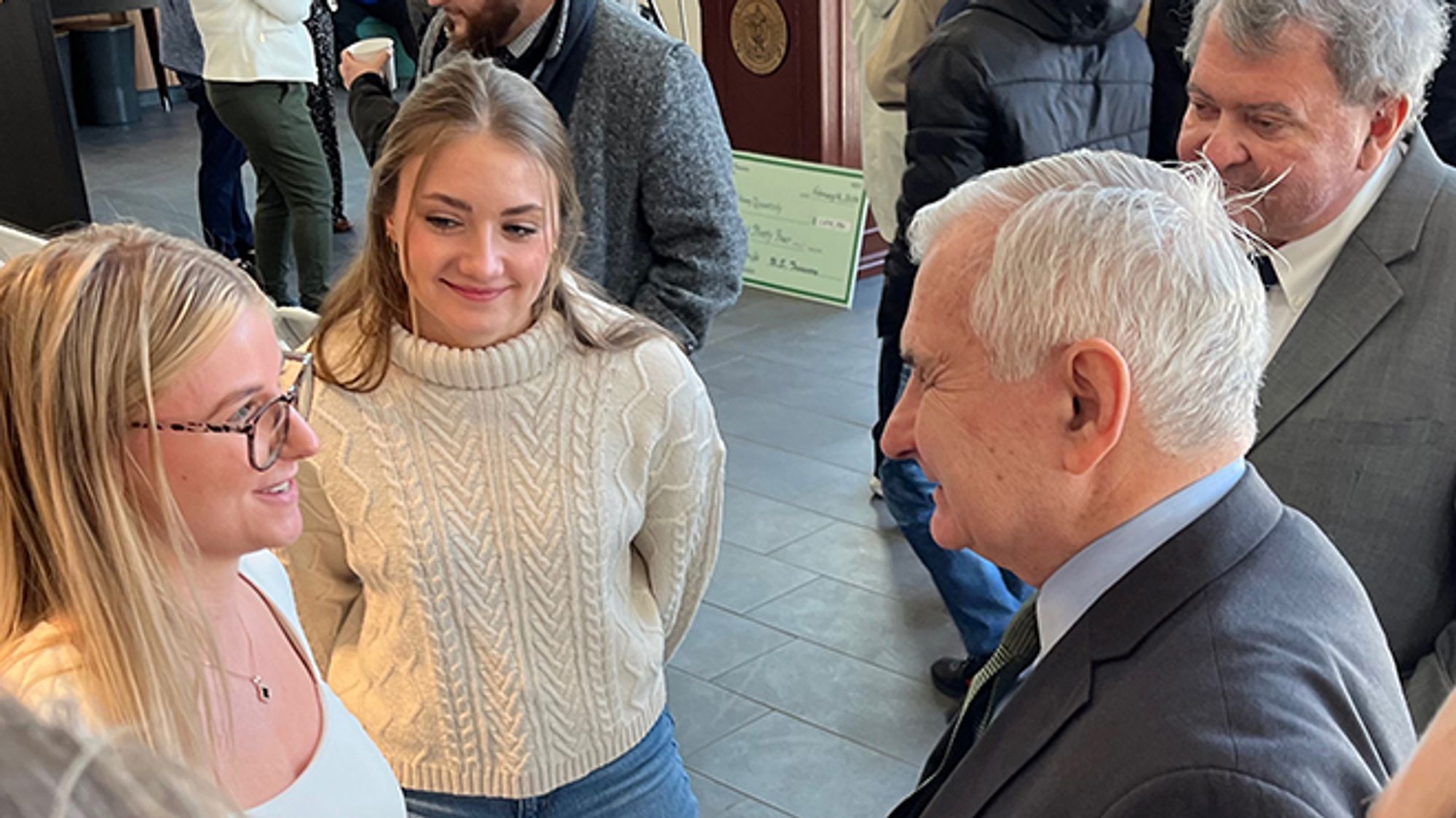 Senator Reed speaking with two female undergraduate researchers.