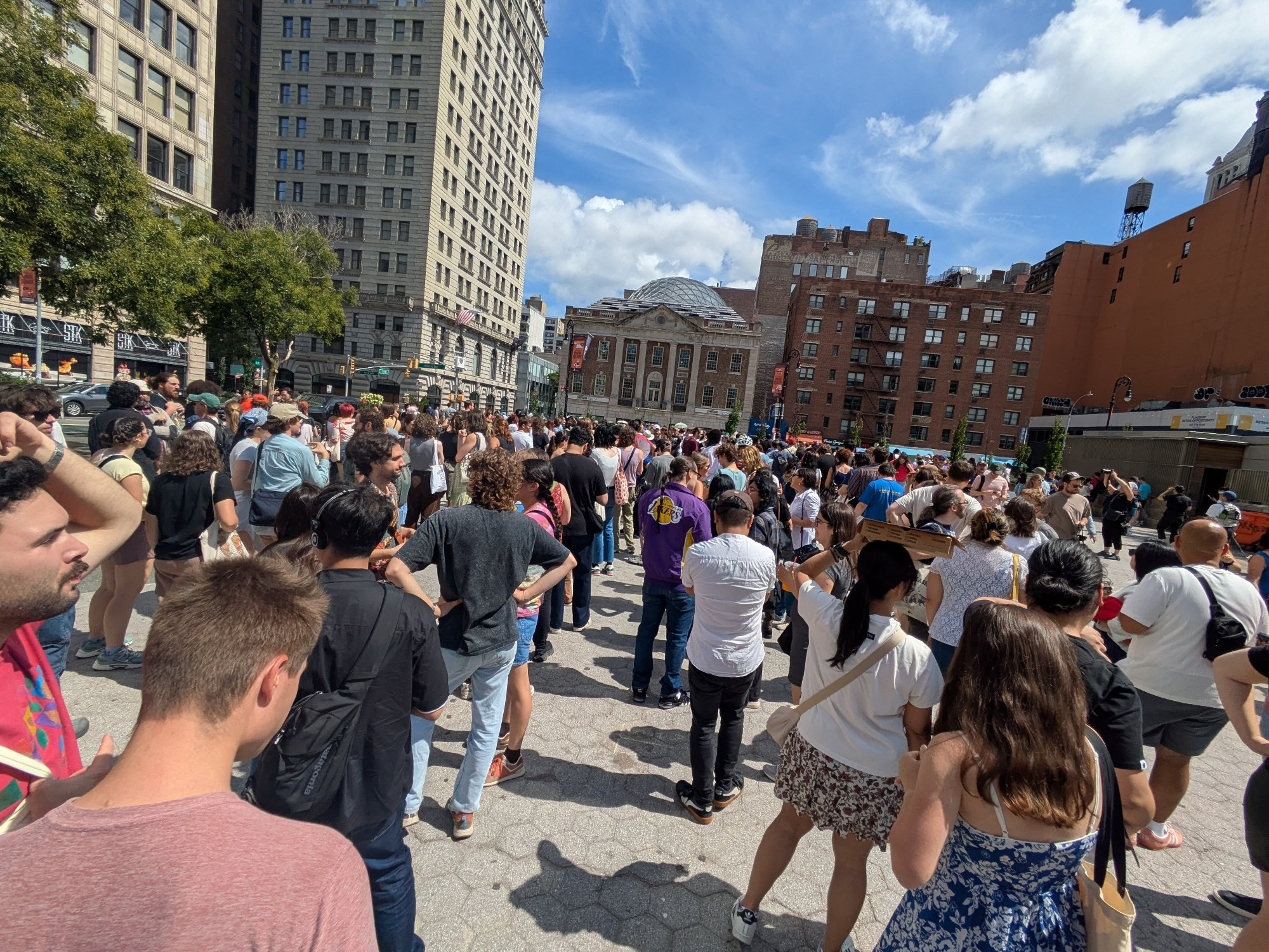 A large crowd of people waiting at union Square for scavenger hunt cards for an event organized by Zohran Mamdani's election campaign