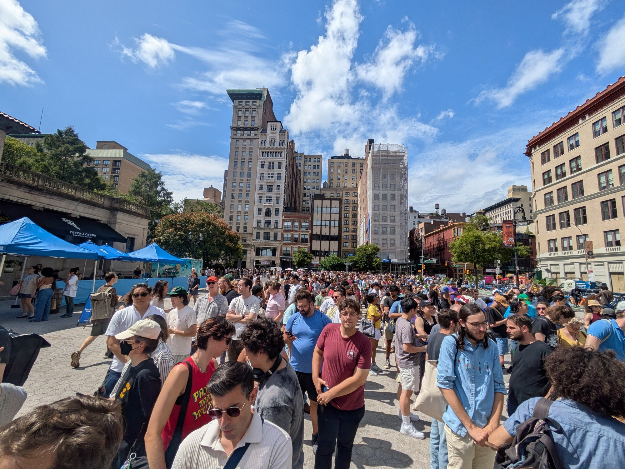 A large crowd of people waiting in five linees at union Square for scavenger hunt cards for an event organized by Zohran Mamdani's election campaign
