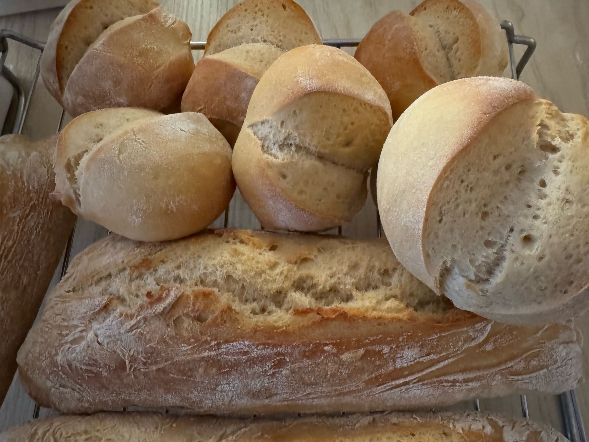 Brötchen und Baguette auf einem Abkühlgitter.