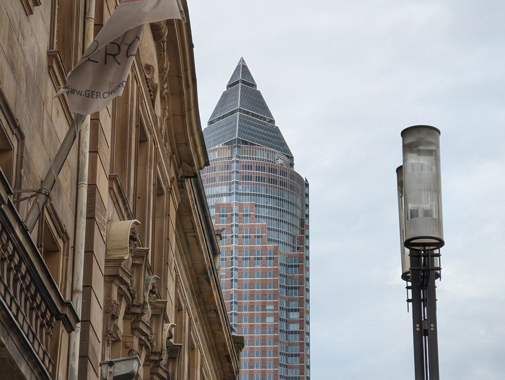 Frankfurter Messeturm guckt hinter einer Hausfassade raus