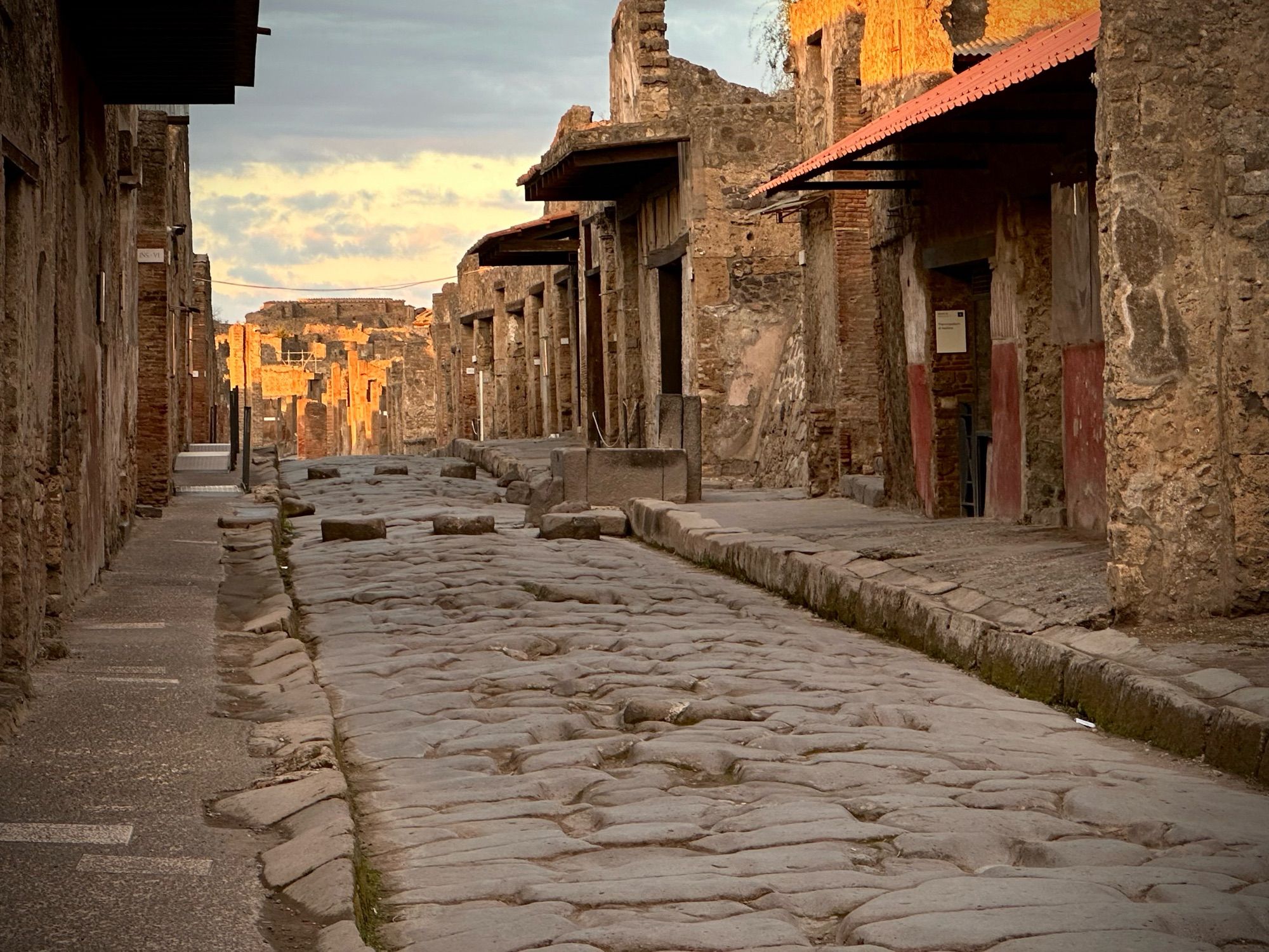 View down the main road in Pompeii with the warm glow of morning light on the walls in the distance