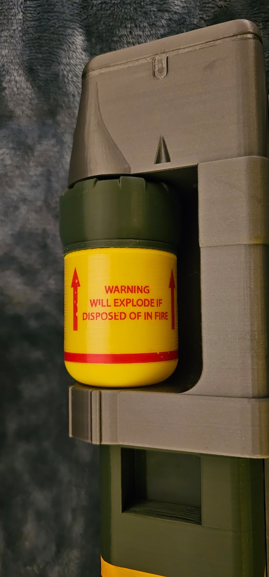 A close up shot of a 3D printed fusion cell (laser weapon ammo) from the game Fallout 4. A sticker on it reads "warning, will explode if disposed of in fire". The cell is missing a few details I need to work on tomorrow.