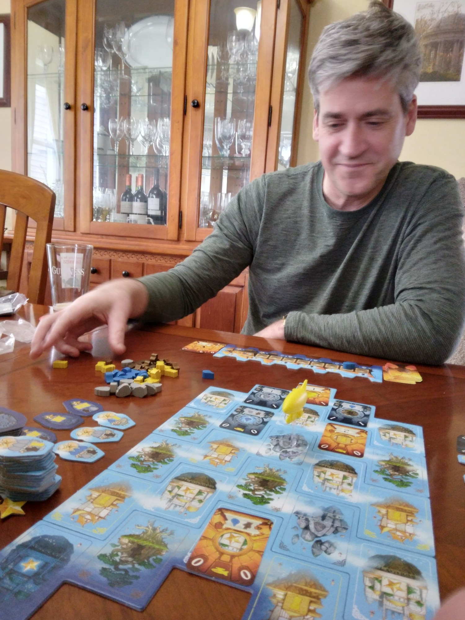 A man is playing a board game.
Players place cards onto the board to pick up resources or deliver goods.