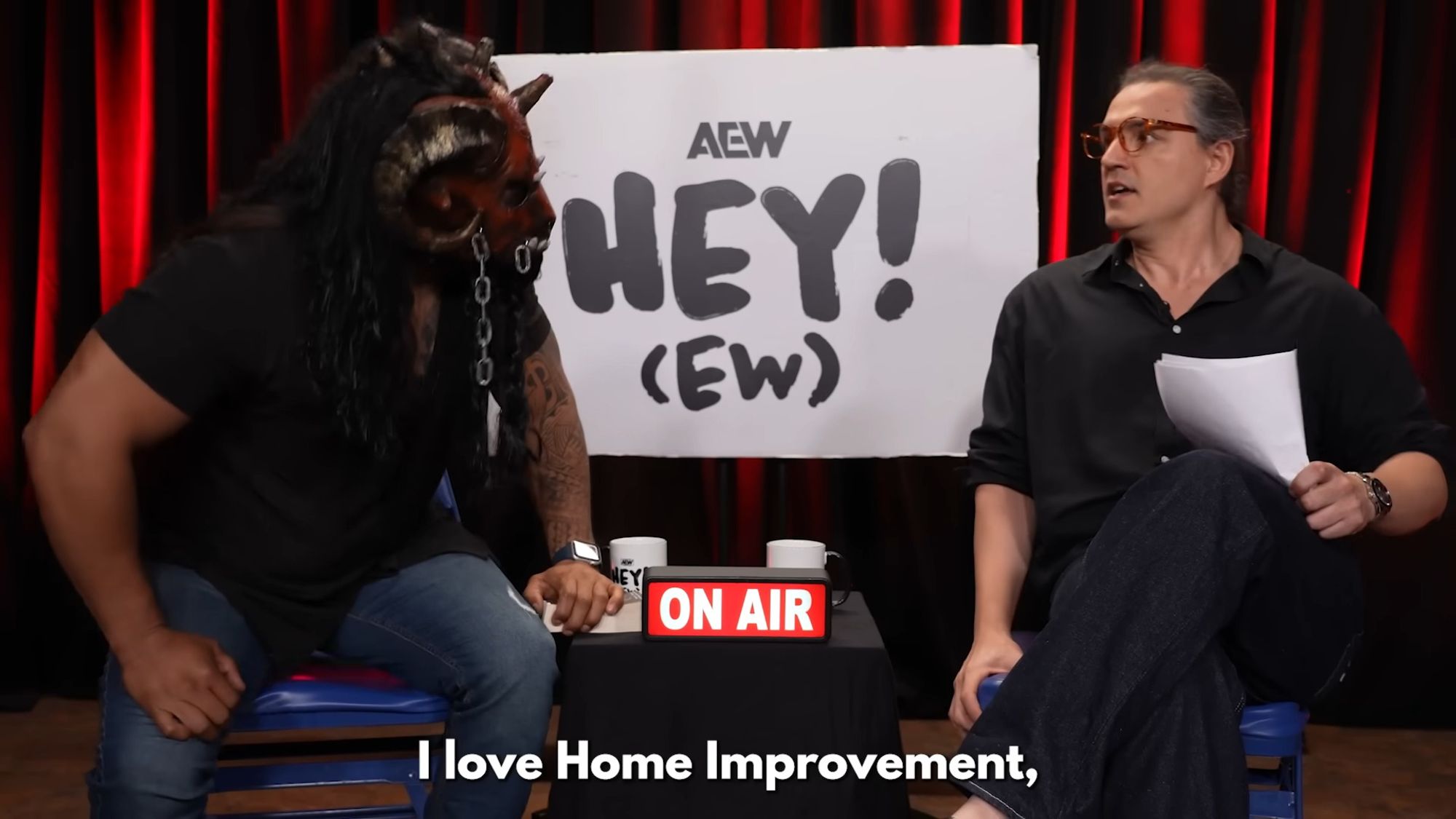 RJ City and The Beast Mortos in front of an AEW Hey! (EW) sign with an ON AIR sign on. Caption is "I love Home Improvement," 