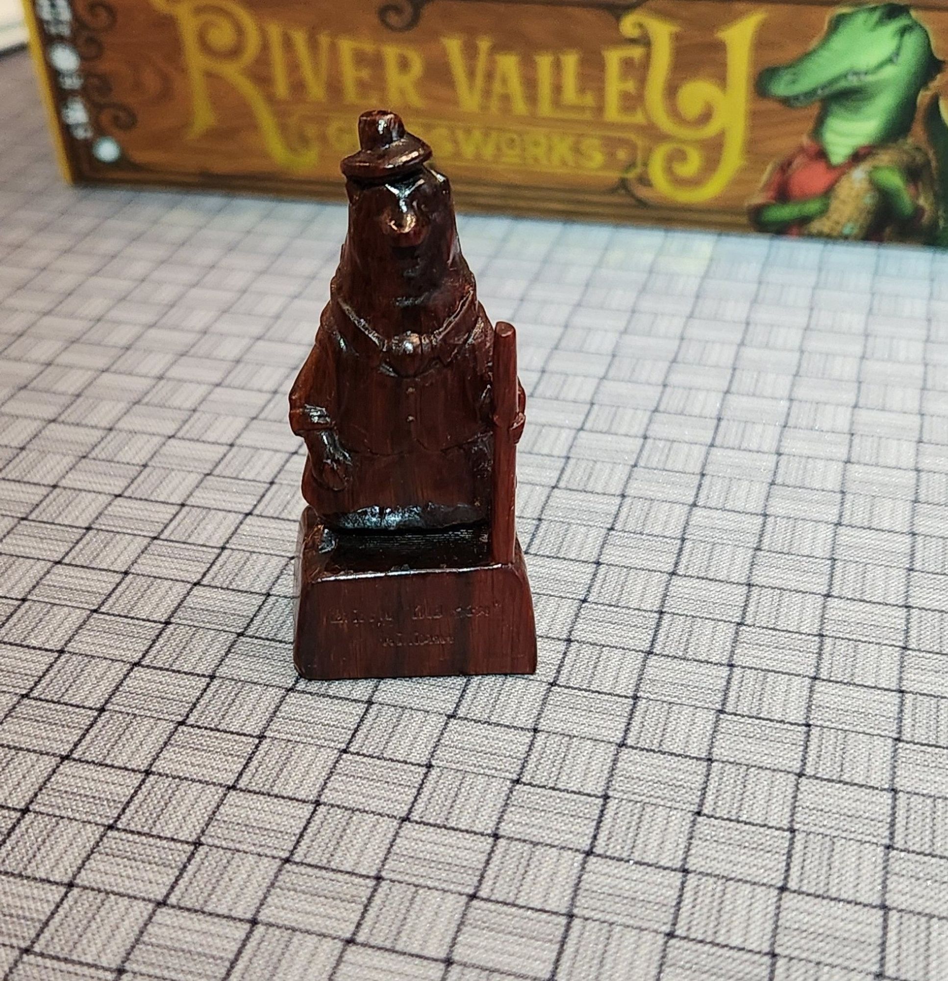 Wooden figure of grizzly bear statue in a hat and vest holding a walking stick.