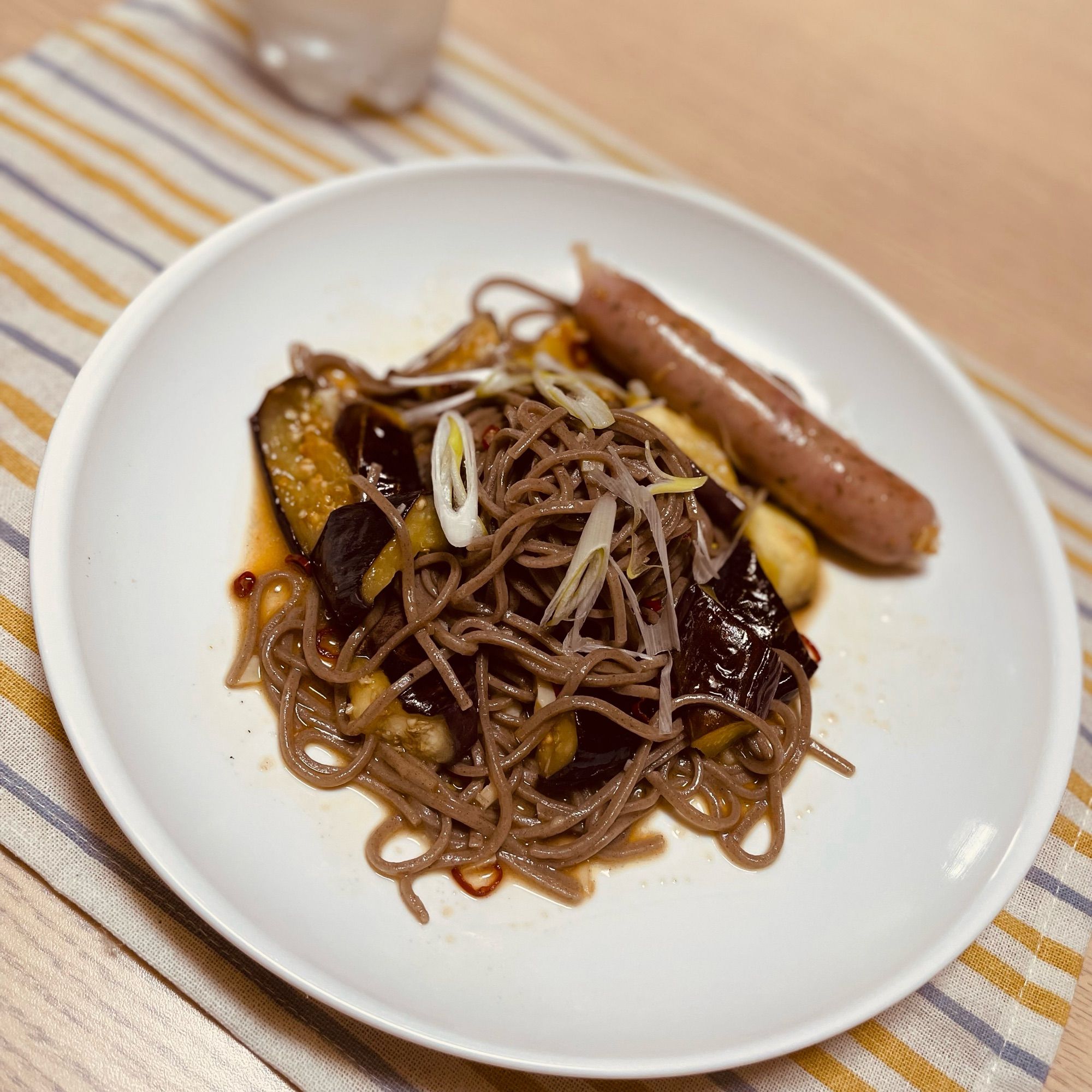 蕎麦と茄子のペペロンチーノ風とレモン＆パセリ風味のフランクフルト。あと炭酸水。