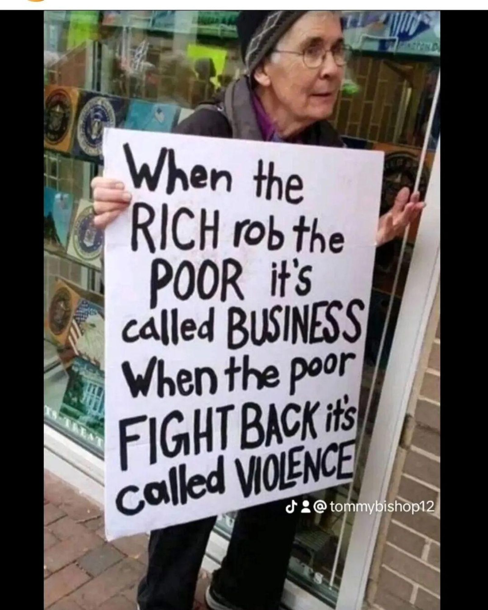 Frau mit transparent, when the rich r.ob the poor it's called business when the poor fight back it's called violence