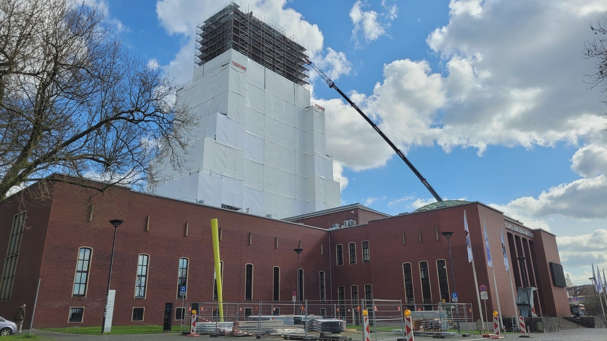 Förderturm mit Gerüst und fast vollständig mit weißen Planen eingehüllt für anstehende Restaurationsarbeiten