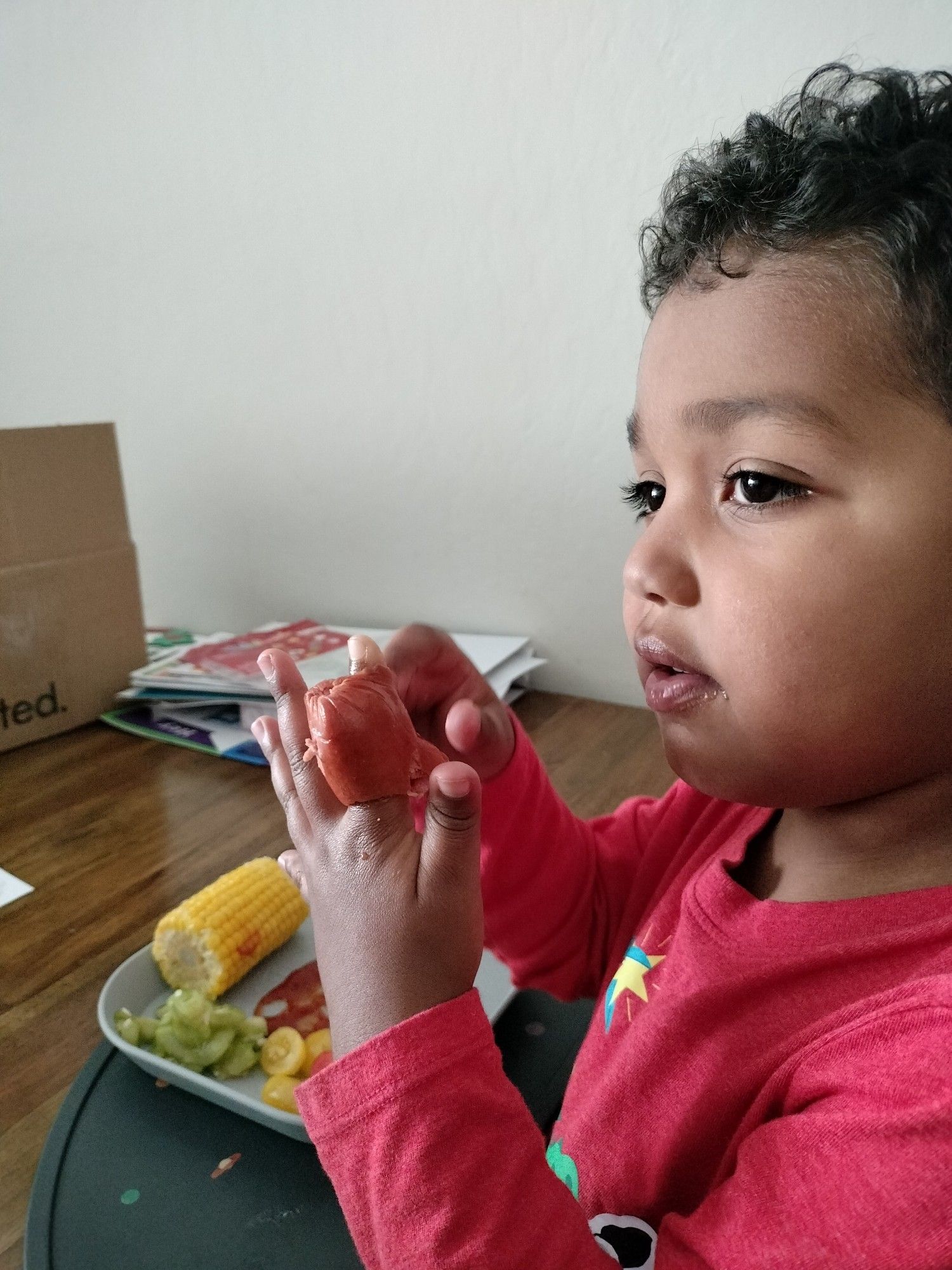 Three-year-old with a hot dog on his finger