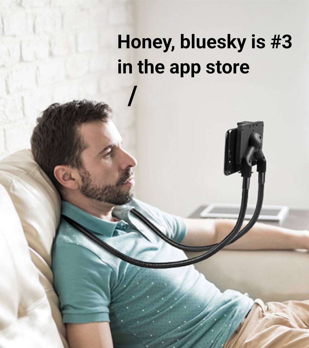 A man looking kinda dejected with a phone mount wrapped around his neck for hands free use saying honey bluesky is #3 in the app store 