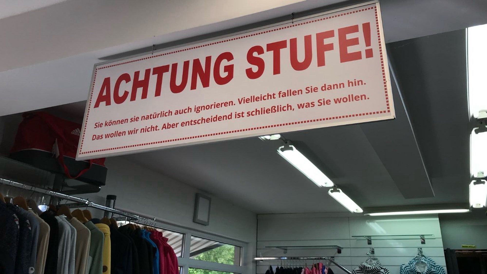 Ein Schild an der Decke eines Lädchens:
„ACHTUNG STUFE!
Sie können Sie natürlich auch ignorieren. Vielleicht fallen Sie dann hin. Das wollen wir nicht. Aber entscheidend ist schließlich, was Sie wollen.“