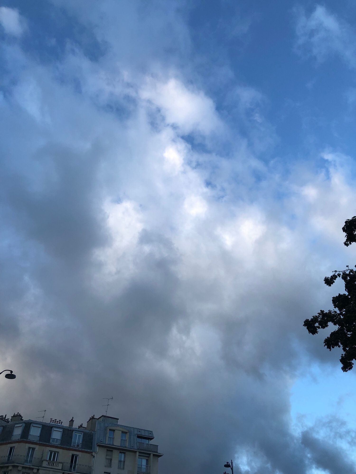 Gros nuages différents tons blanc, gris avec un coin de sel bleu au-dessus des toits