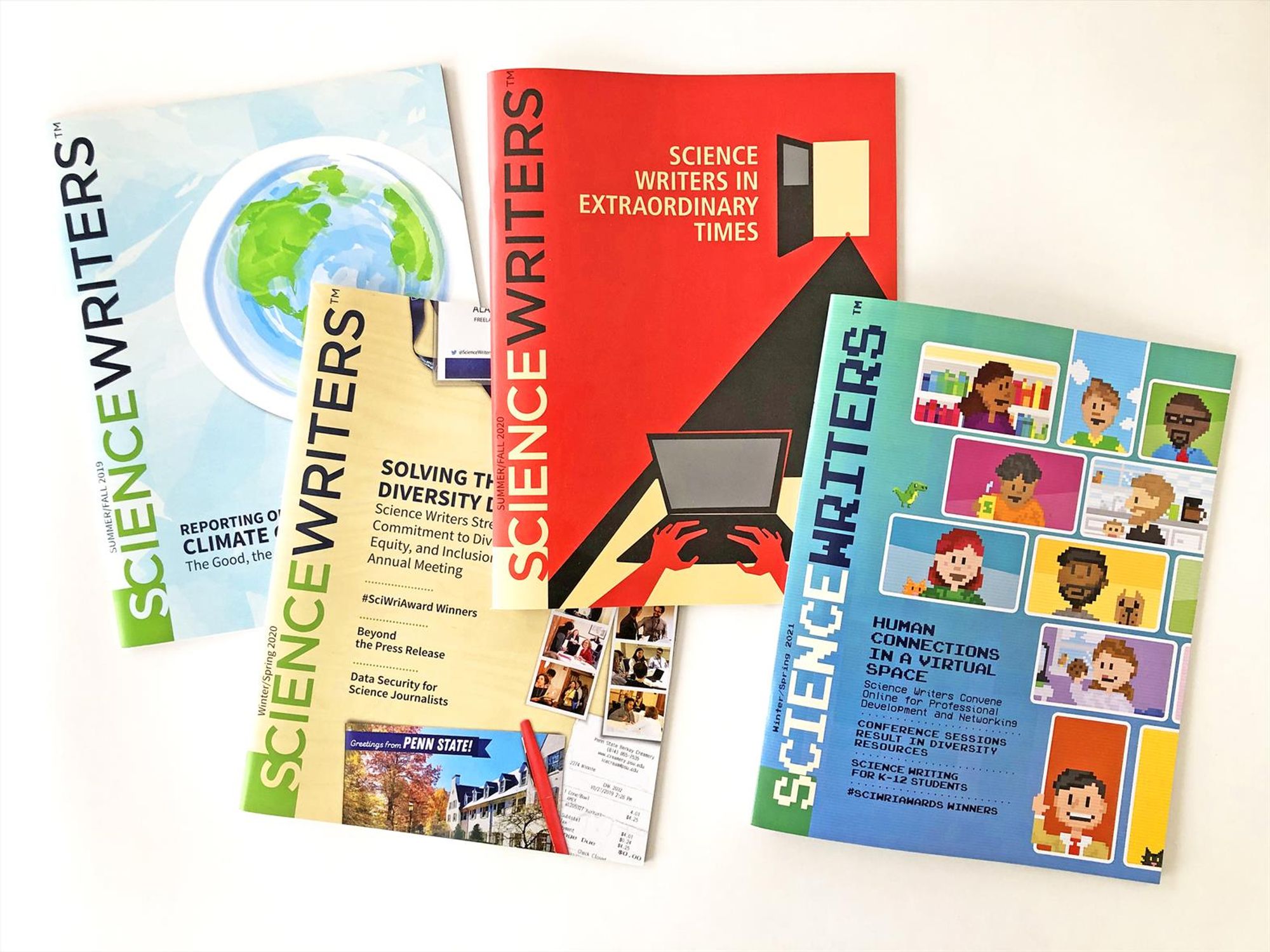 Photo of the covers four issues of Science Writers magazine. One cover has planet earth in a paper cutout style; one cover resembles a photorealistic desk full of travel receipts and mementos; one cover is in sharp, bold blocks reminiscent of a Alfred Hitchcock film poster; and the last cover uses a pixelated, computer cartoon style.