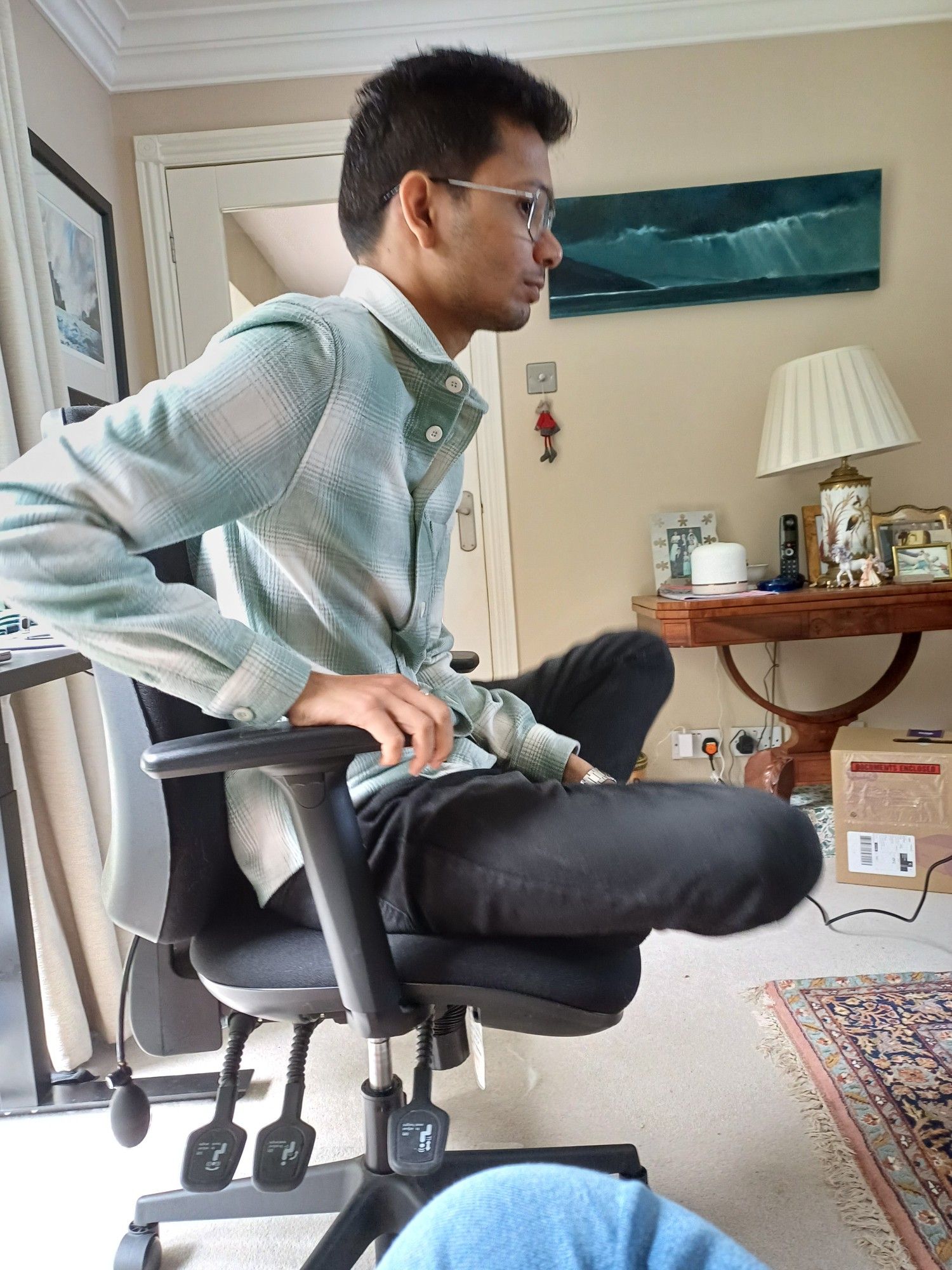 Anirudh perched cross-legged on a swivel chair listening to a presentation