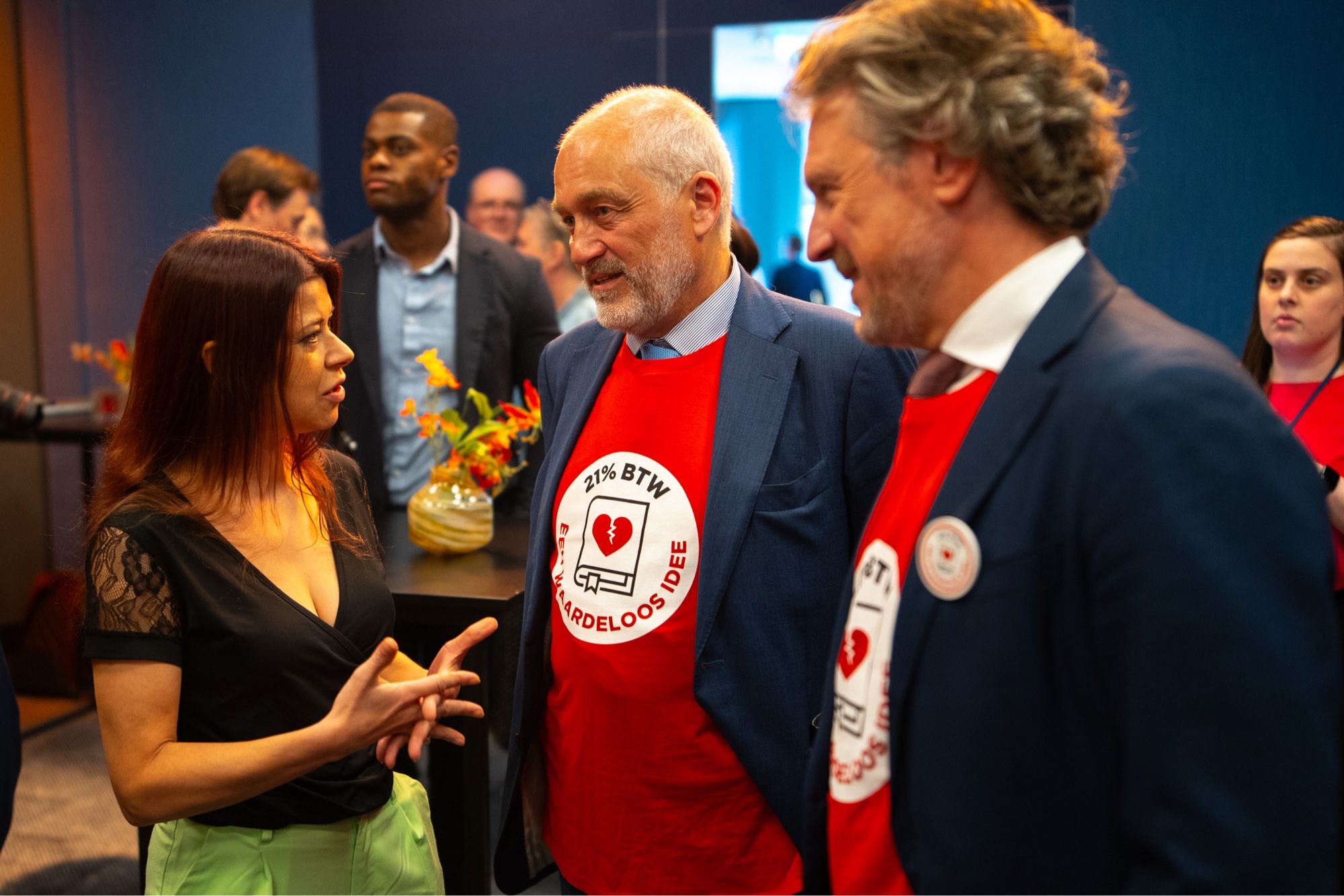 Foto in perscentrum Nieuwpoort waar ik in gesprek ben met twee initiatiefnemers die beide een rood shirt met daarin het logo van de petitie dragen: witte cirkel met 21% btw, waardeloos idee