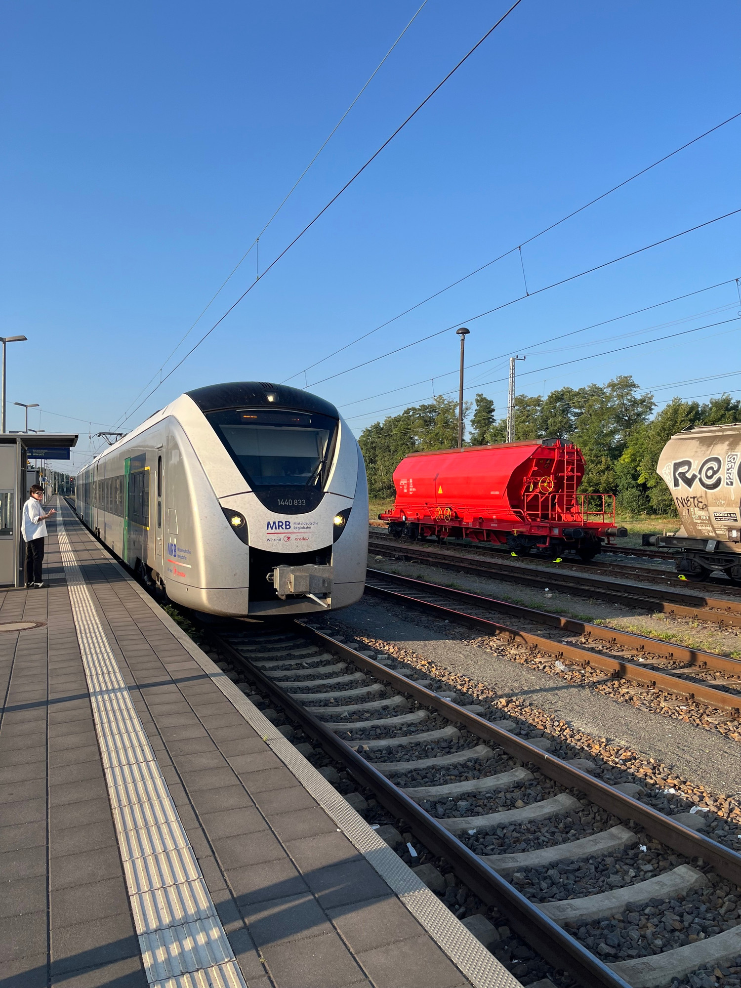 Coradia EMU in front of a red freight waggon 