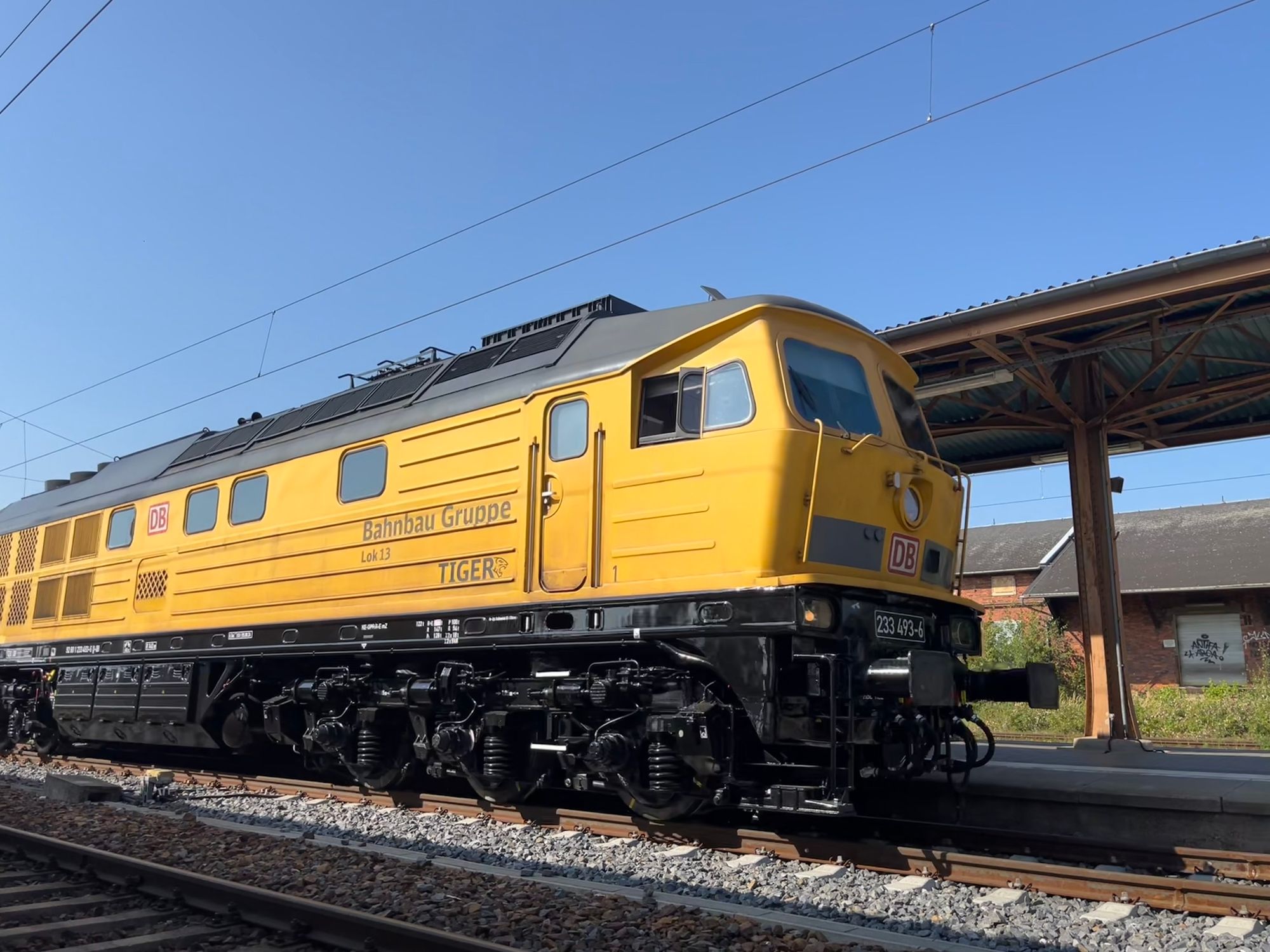 A yellow and black huge heavy diesel locomotive. Behind it a station canopy