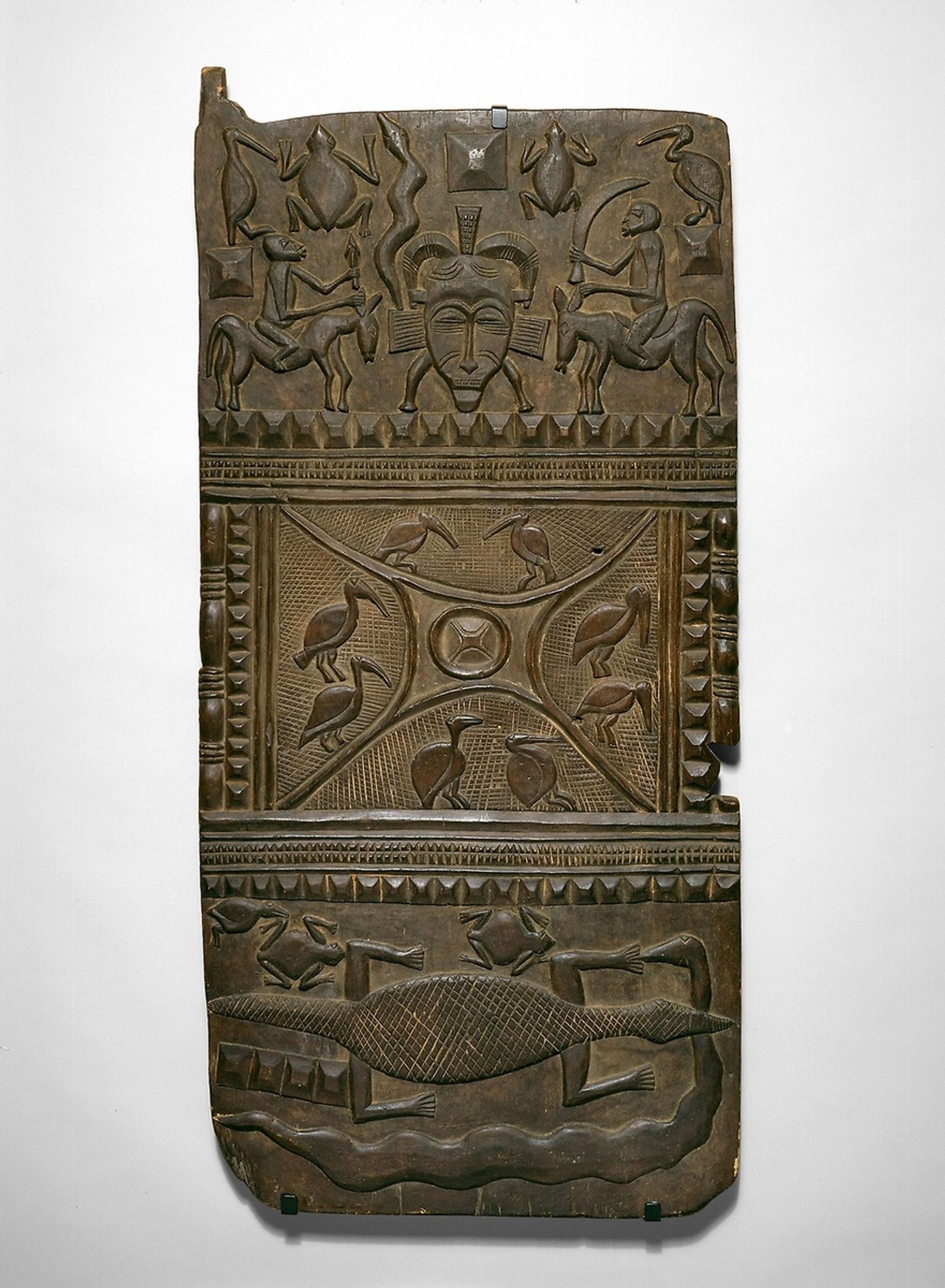 Nyaamadyo Koné worked in the vicinity of the influential regional woodcarving center of Kolia, and was among very few Senufo artists of the 20th century to achieve fame for making doors with bas-relief decorations of this size and complexity. Carved on commission, this door adorned a small building that served as a shrine and consultation room for a ritual specialist. Its images of animals and face masks evoke sources of natural and supernatural power.

Restricted gift of Anita Glaze, Marshall Field, and Robert J. Hall; through prior gifts and acquisitions of various donors