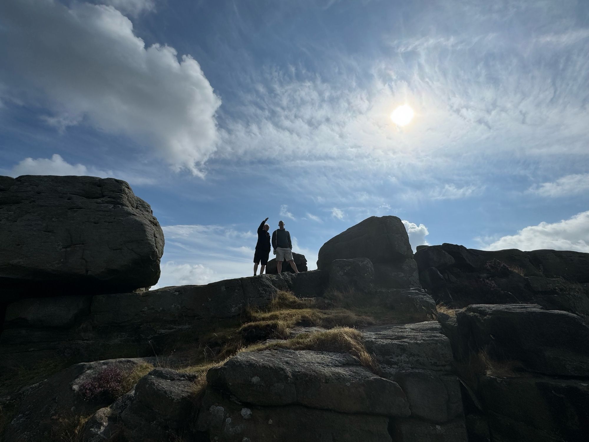 Two Silhouetted figures in the sunlight standing on the edge of an outcrop