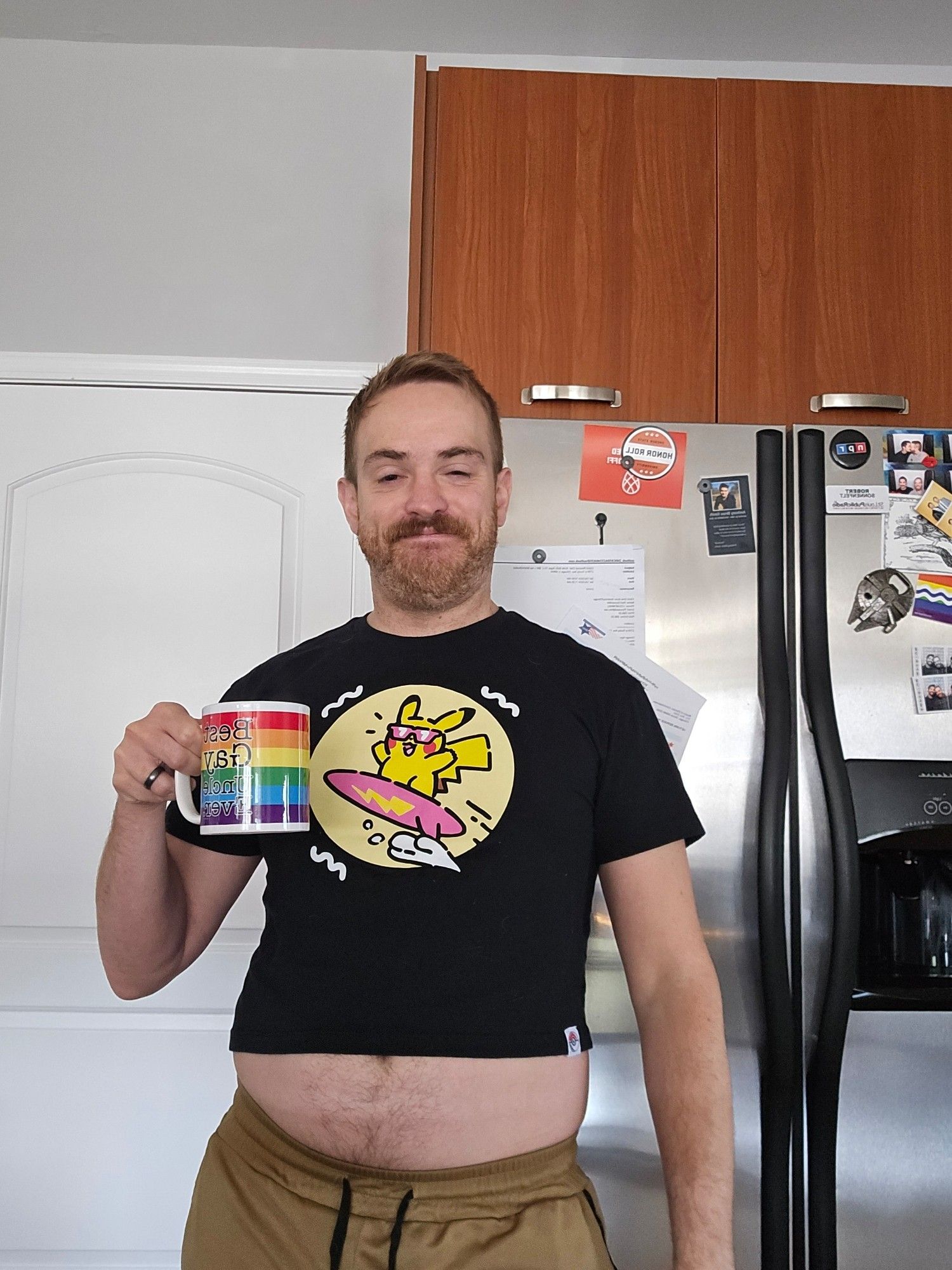 Jake in a crop top with a surfing Pikachu on it. Holding a cup of coffee