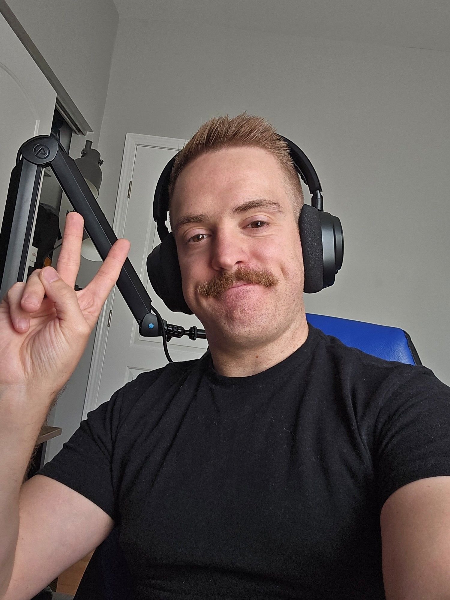 Selfie of Jake doing a peace sign in a black shirt. He is wearing gaming headphones