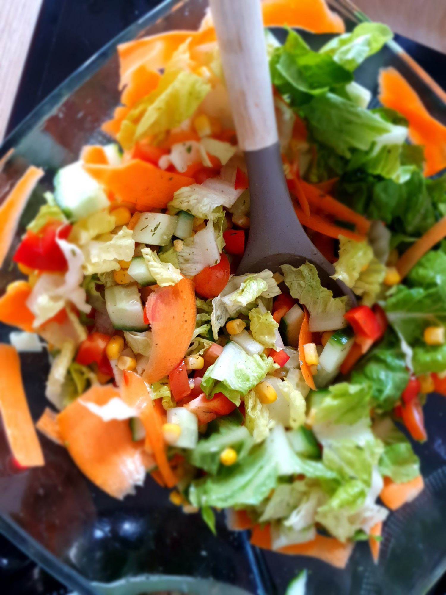 Bunter Salat aus Möhren, Gurken, Tomaten, roter Paprika und Mais in einer Glasschüssel von oben fotografiert 