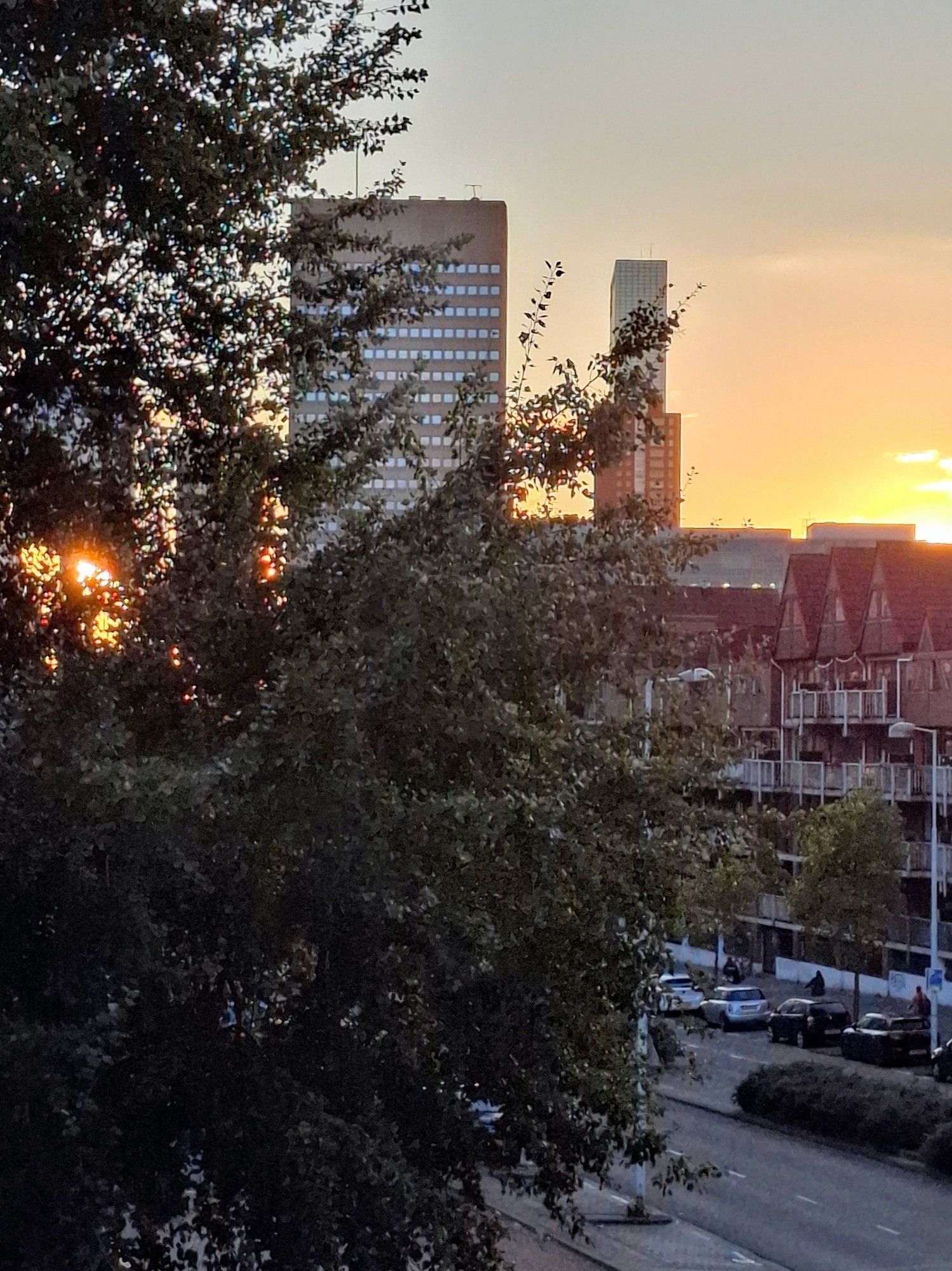 De zon die onder gaat met een oranje gele gloed achter de huizen in Rotterdam