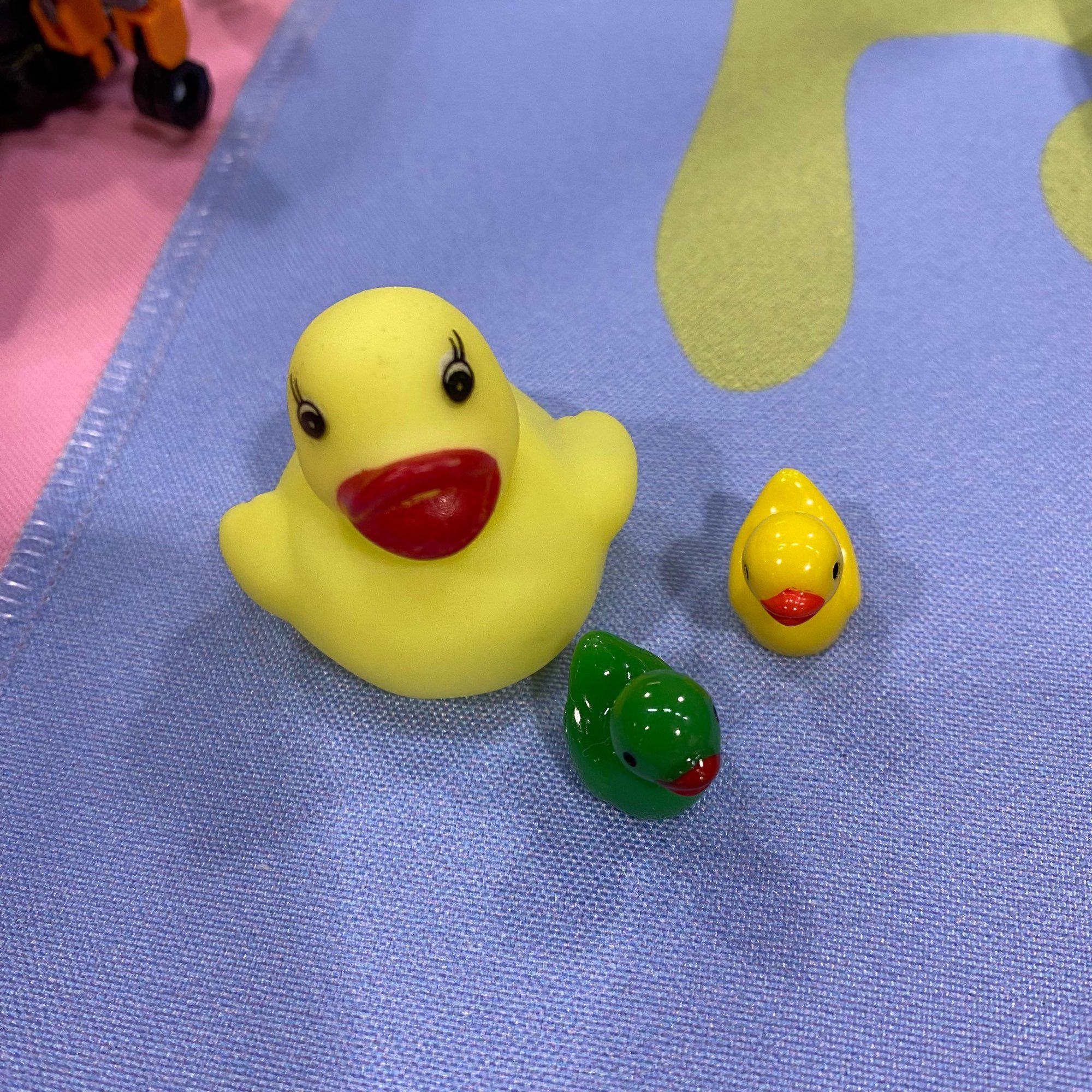 Picture of three rubber ducks. One big yellow, one small yellow one, and one small green one.