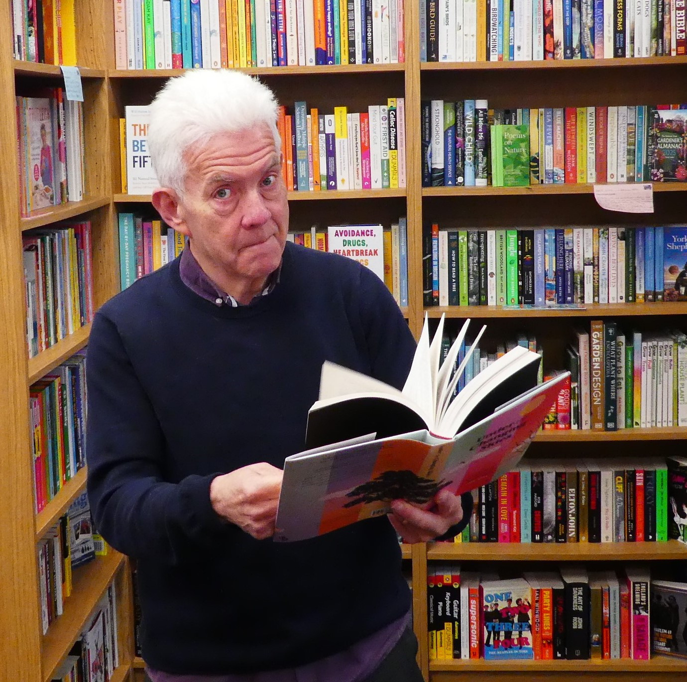 Photo of Ian McMillan, pretending to read a book he has signed.