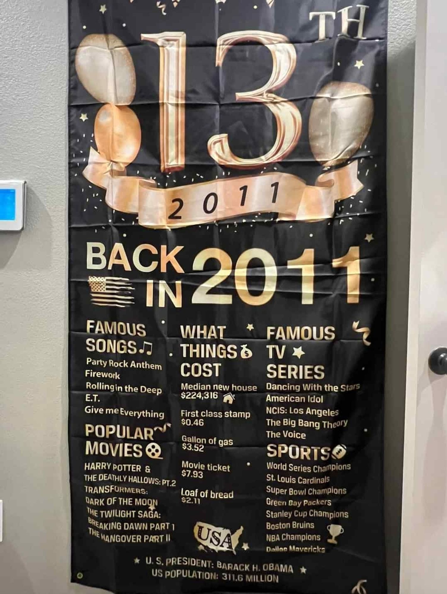 A black banner with gold text that says 13th back in 2011. Famous songs, party Rock anthem, firework, rolling in the deep, ET, Give Me Everything. Popular movies Harry Potter and the deathly hallows, transformers, The Twilight saga, The hangover part 2. What things cost new house $224,316, first class stamp 46 cents, gallon of gas $3.52. movie ticket $7.93, loaf of bread $2 11 cents. Famous TV series dancing with the Stars, American Idol, NCIS Los Angeles, The Big bang theory, The voice. Sports, World series champion St Louis Cardinals super bowl champions Green Bay Packers Stanley cup champions Boston bruins NBA champions Dallas Mavericks. US President Barack Obama US population 311.6 million.