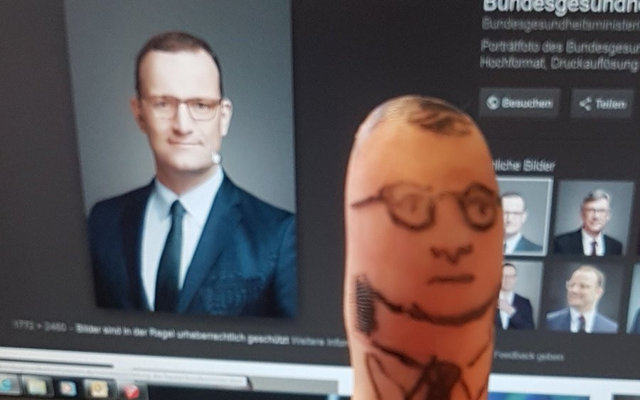 Jens Spahn,  auf einen Daumen gemalt,,im Hintergrund das "Original" 