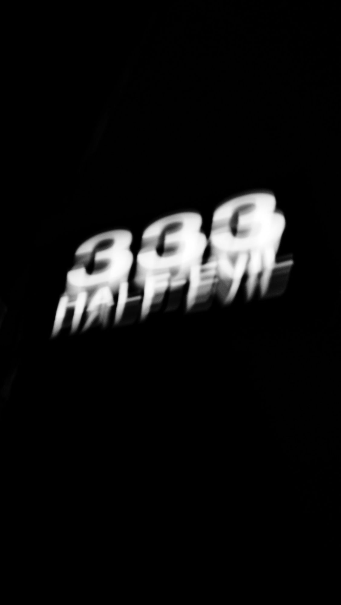 Nighttime. A street sign that says “333 Half Evil” is viewable mid frame. Extreme camera movement and a long shutter speed create blurring and light trails.