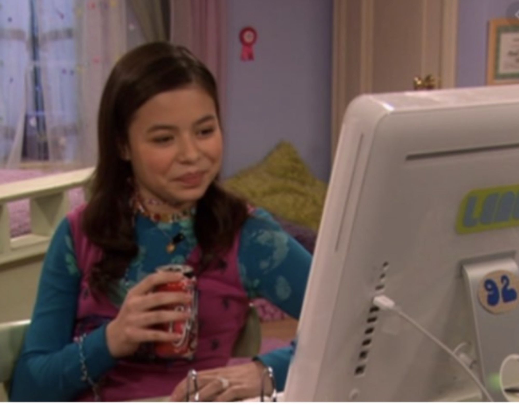 Woman holding a soda looking smugly at her computer monitor