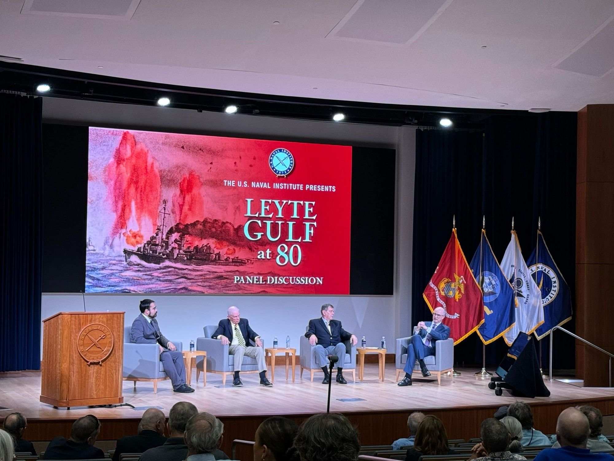 A view of the Leyte Gulf at 80 panel discussion at the Naval Institute with the four panelists seated on the stage.