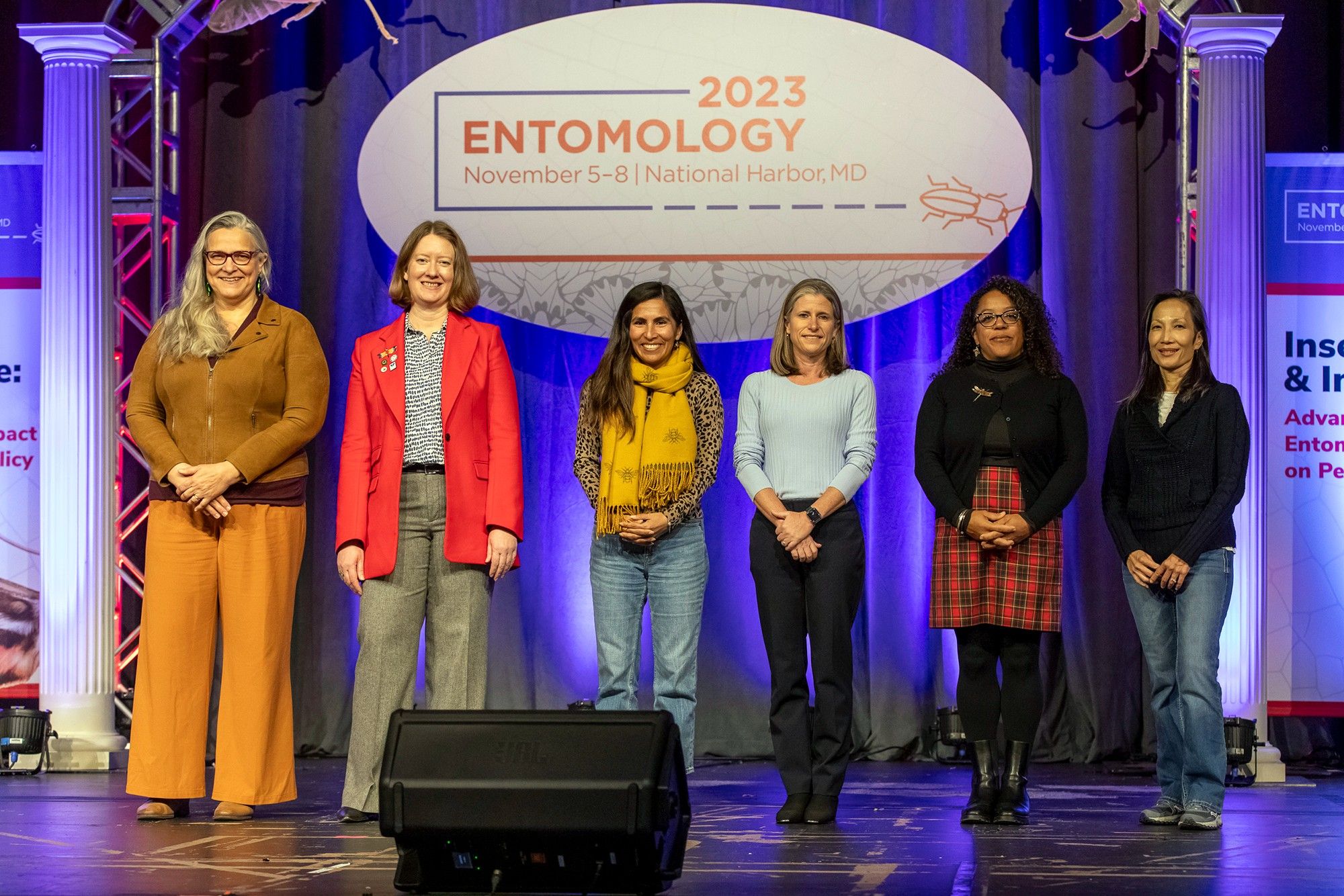 ESA leaders pose on the main stage at Entomology 2023, from left to right: outgoing president Marianne Alleyne, incoming president Jennifer Henke, incoming vice president Lina Bernaola, incoming VP-elect Melissa Willrich Siebert, outgoing past president Jessica Ware, and treasurer Faith Oi.