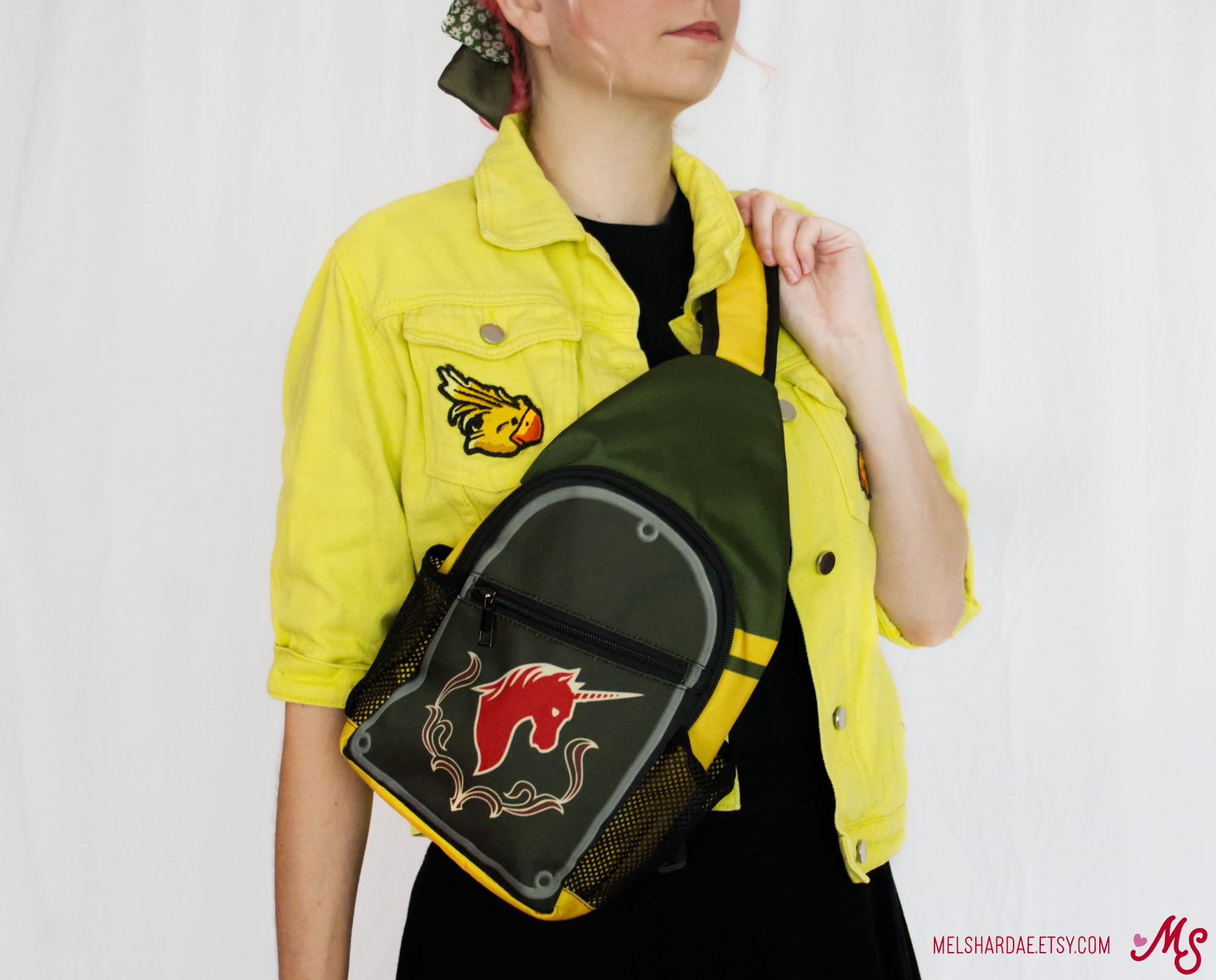 Photo of me modeling my Haurchefant inspired sling bag. It is olive green and grey with yellow accents and the house Fortemps crest on the front