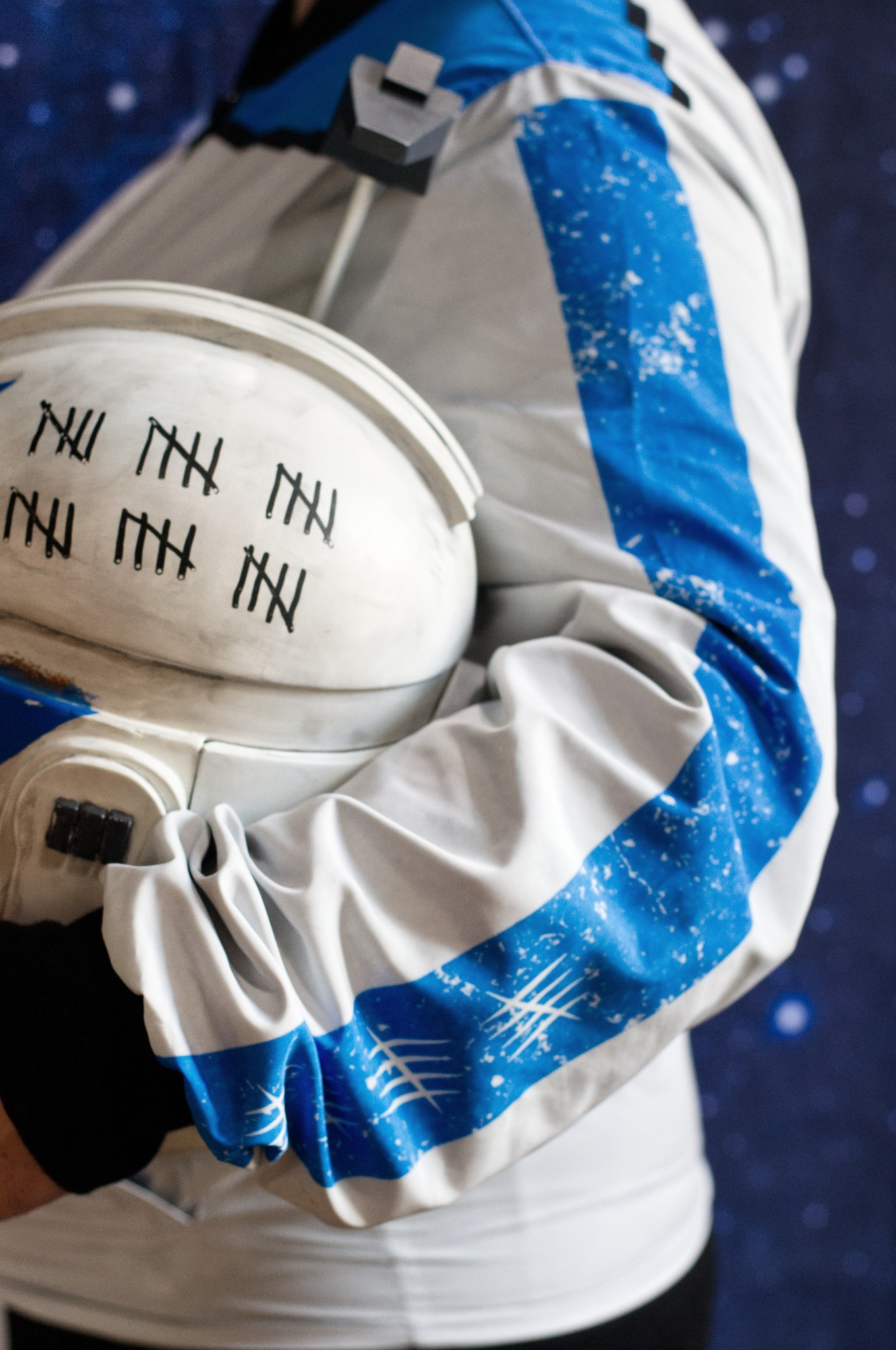 Photo of the side view of a Captain Rex jacket. The model is holding Rex's helmet.