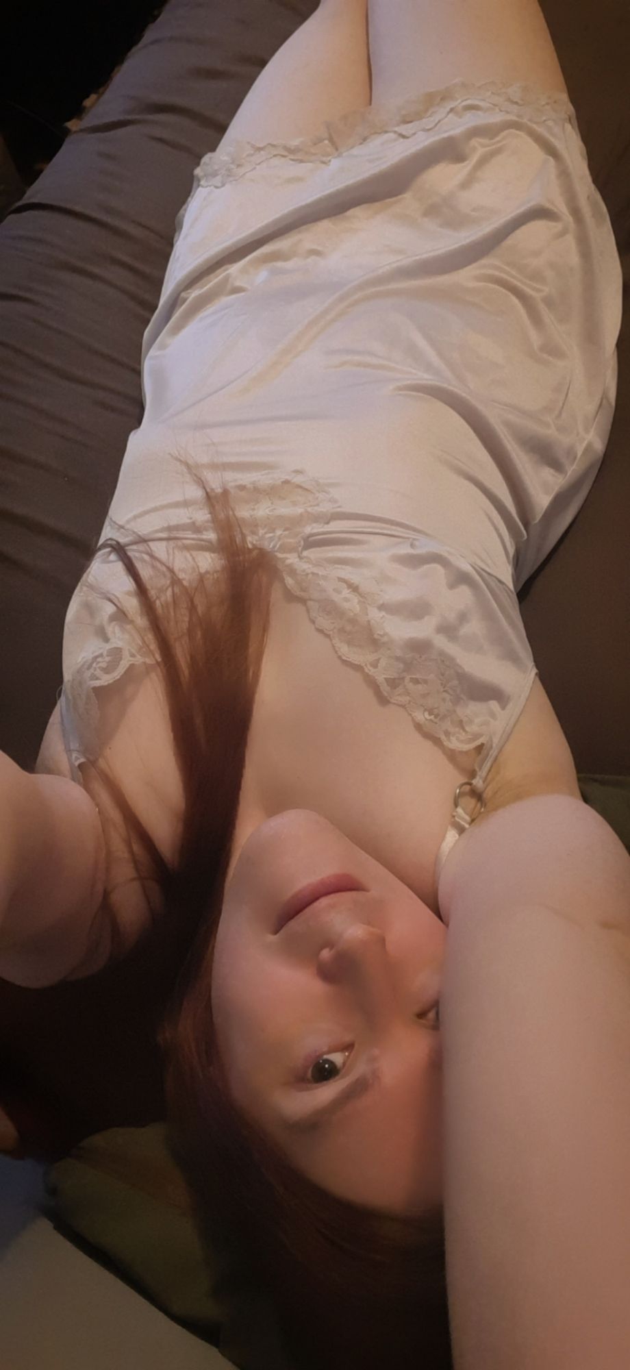 serah laying in bed in a white satin negligee, holding the camera above her