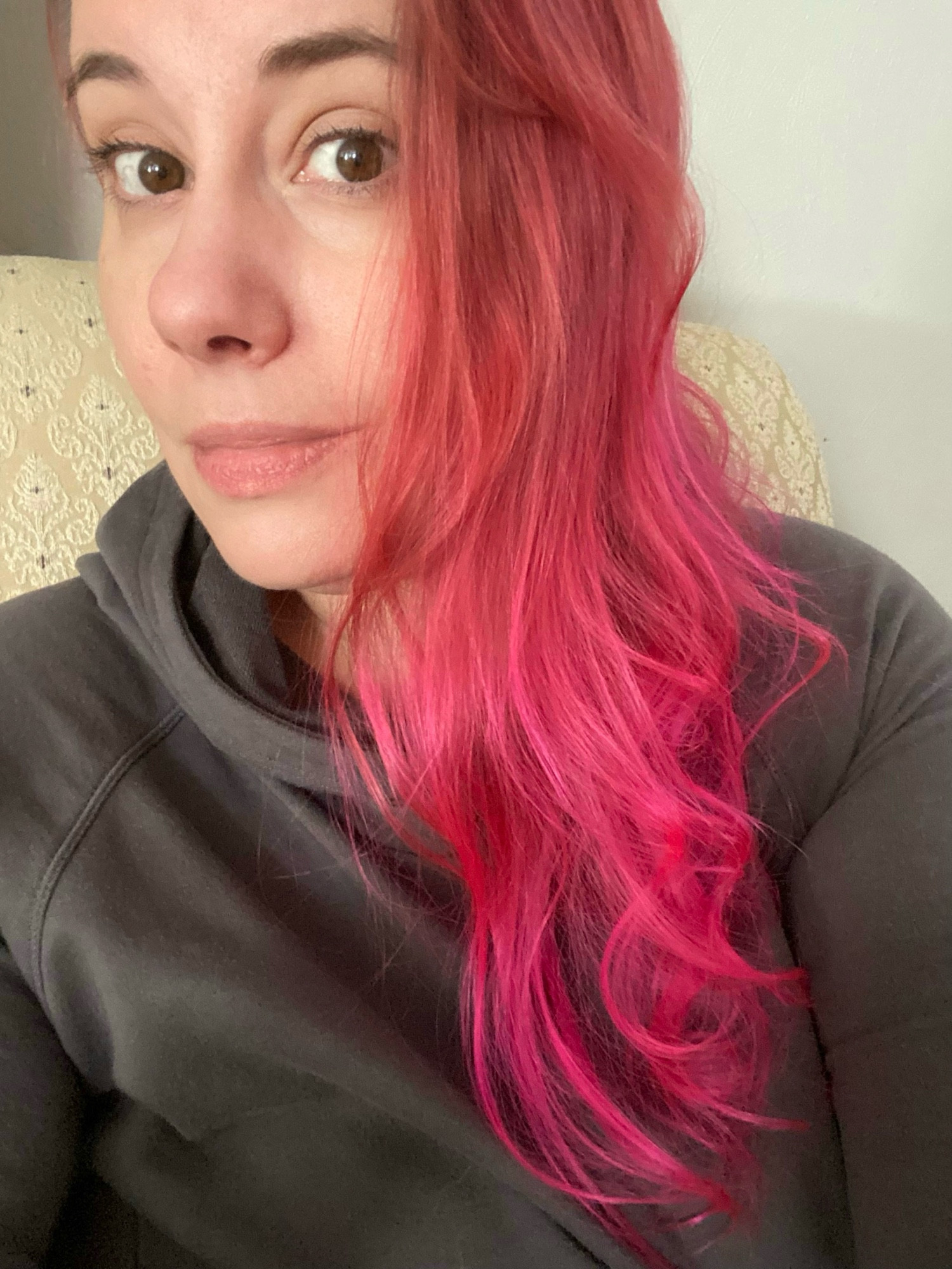 A rare Crista without her glasses pic showing the red to pink color shift in her hair and wearing a grey fitted hoodie