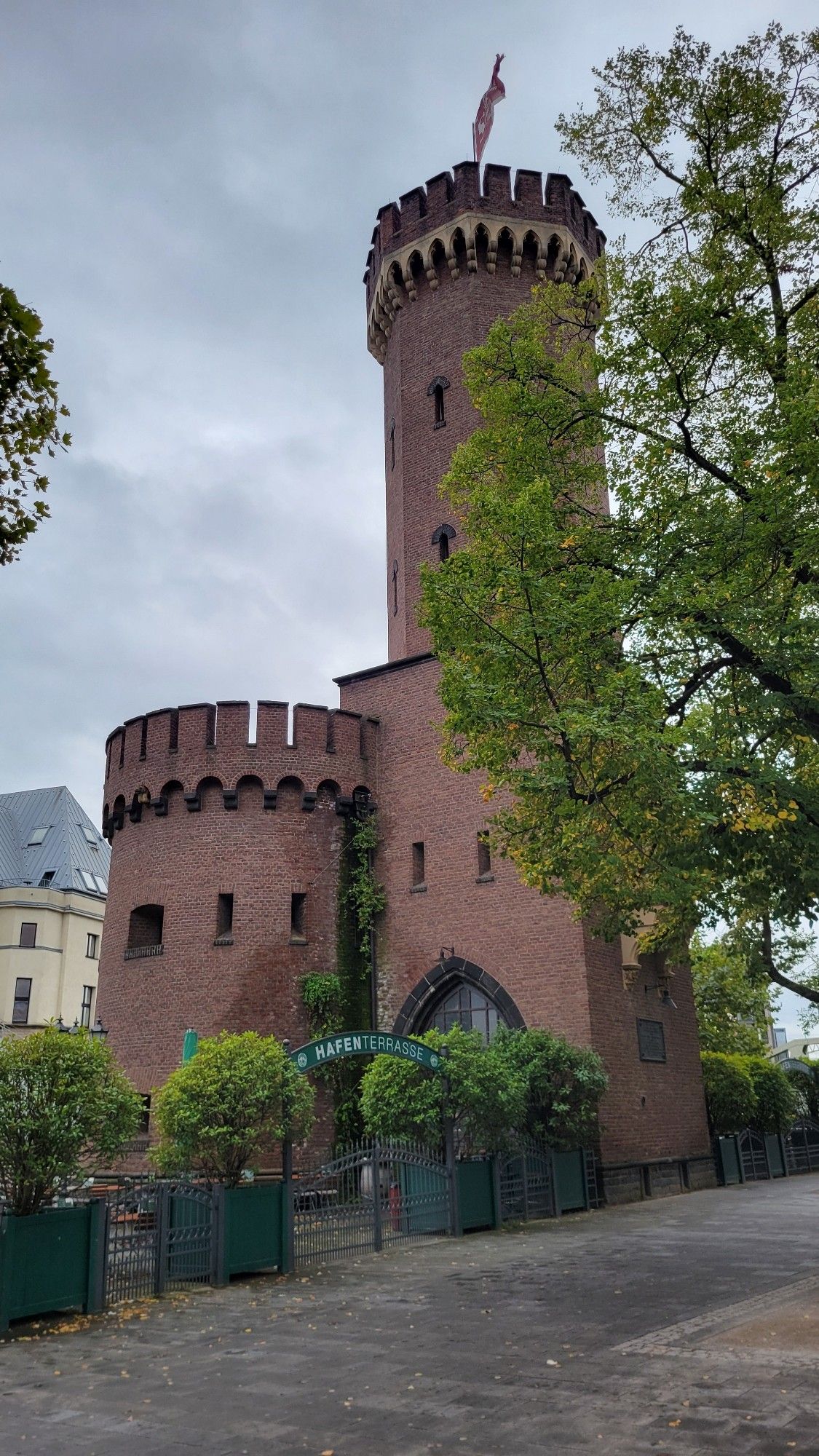 Reddish brick castle tower structure off to the side, on a rainy, cloudy day in Germany