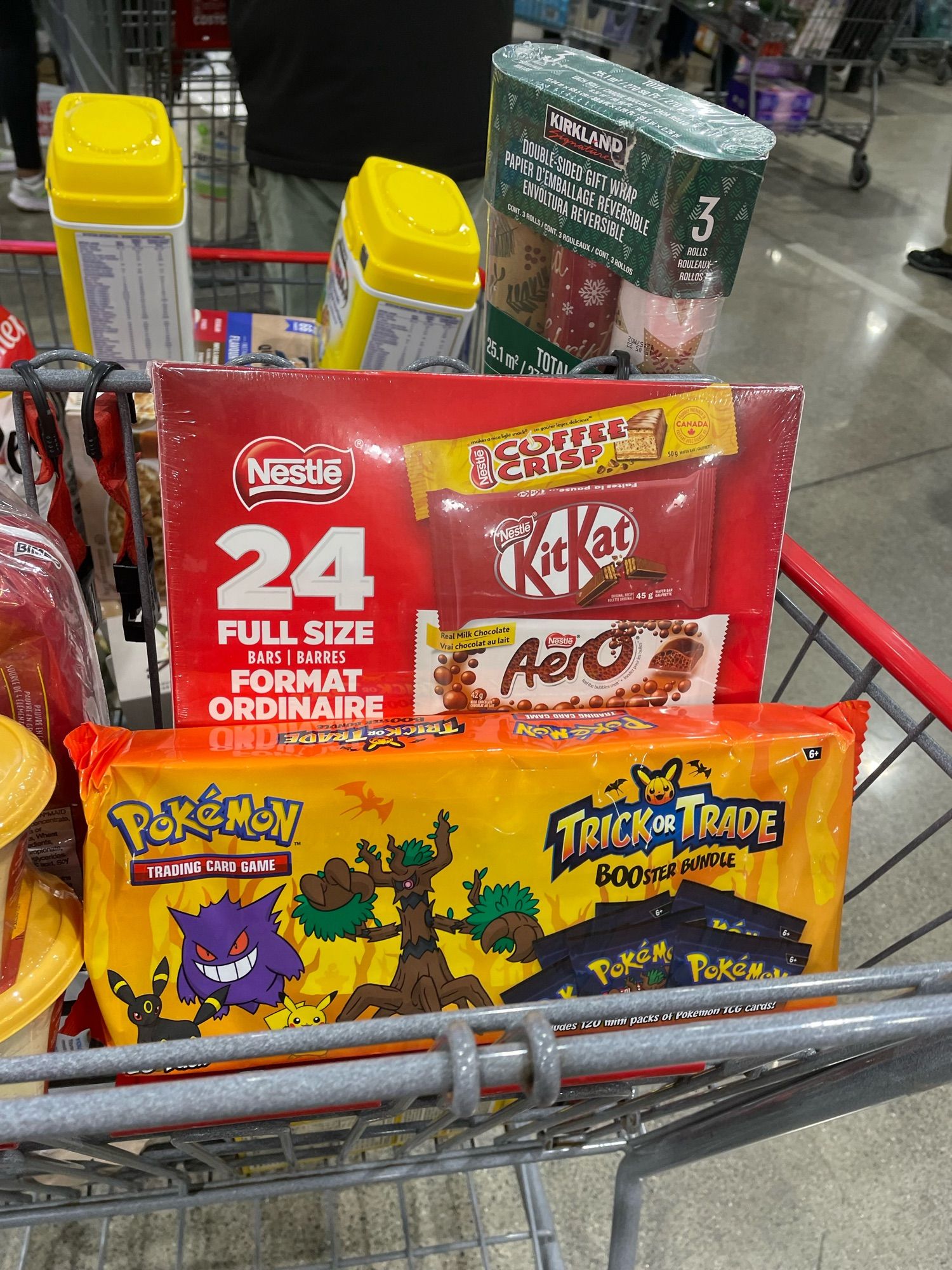 a shopping cart with a box of full sized candy bars and pokemon card halloween booster packs