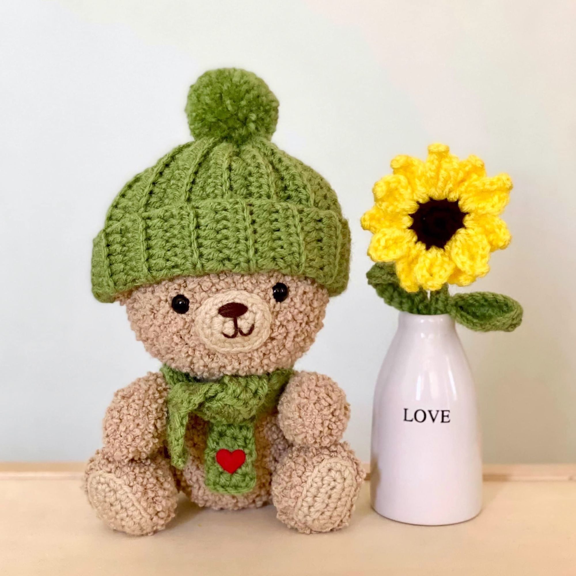 Teddy bear with a crocheted sunflower in a vase with the word “love”