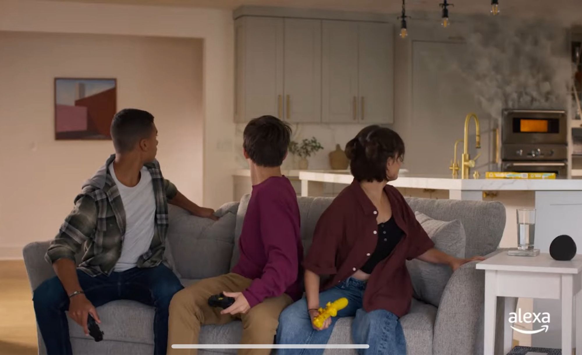 Screenshot from an Amazon Alexa Emergency Assist commercial with three teens sitting on a couch with their necks craned toward a tiny orange glowing oven with smoke pouring out. One shouts “The pizza’s burning!”, another jumps up and runs over to stare at the oven. Presumably they asked Alexa to save them. Instead of, you know, turning the oven off.