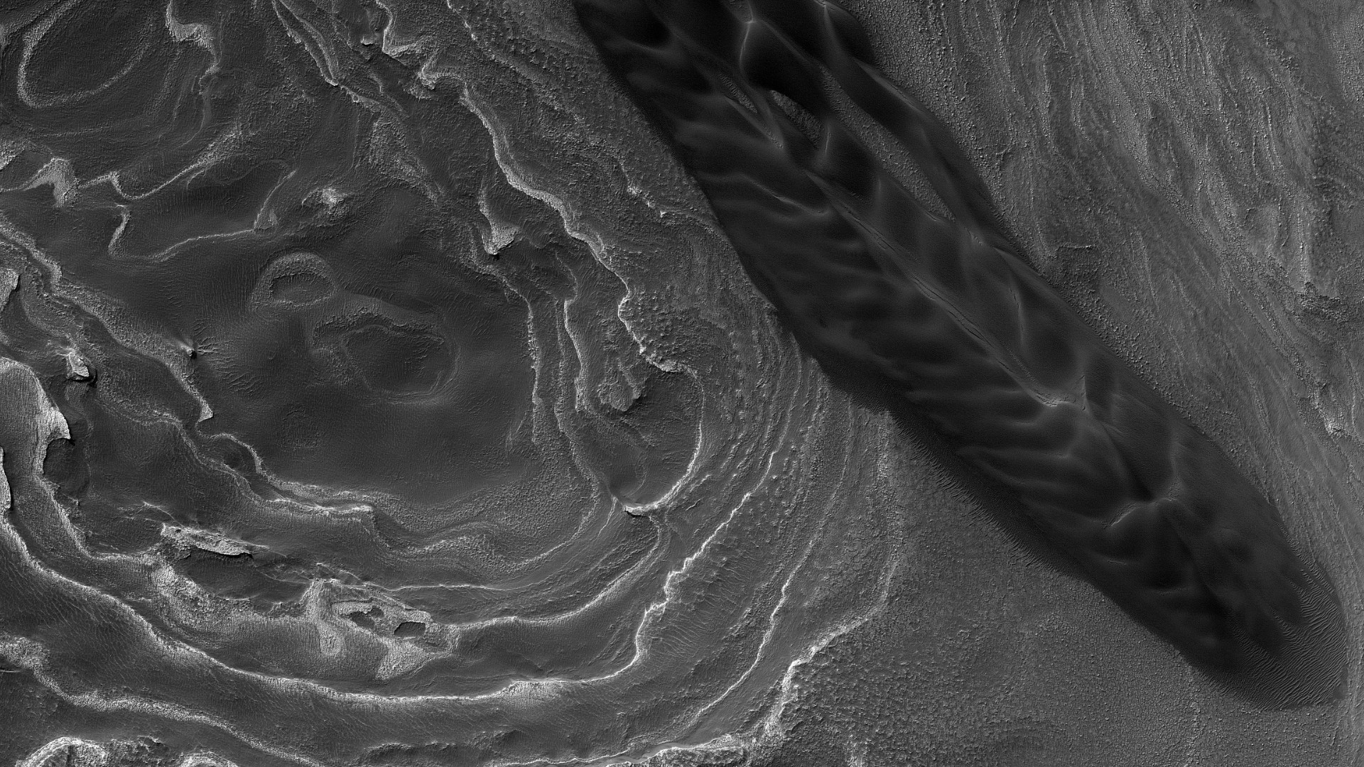 Image shows curving rock layers and large dune streak dominating the scene. Credit: NASA/JPL-Caltech/UArizona