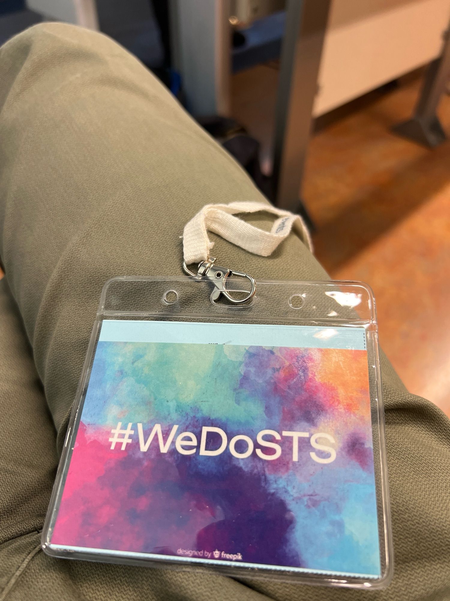 Photograph of a #WeDoSTS sticker (colorful background, white typo) in an EASSt4s2024 conference name tag.