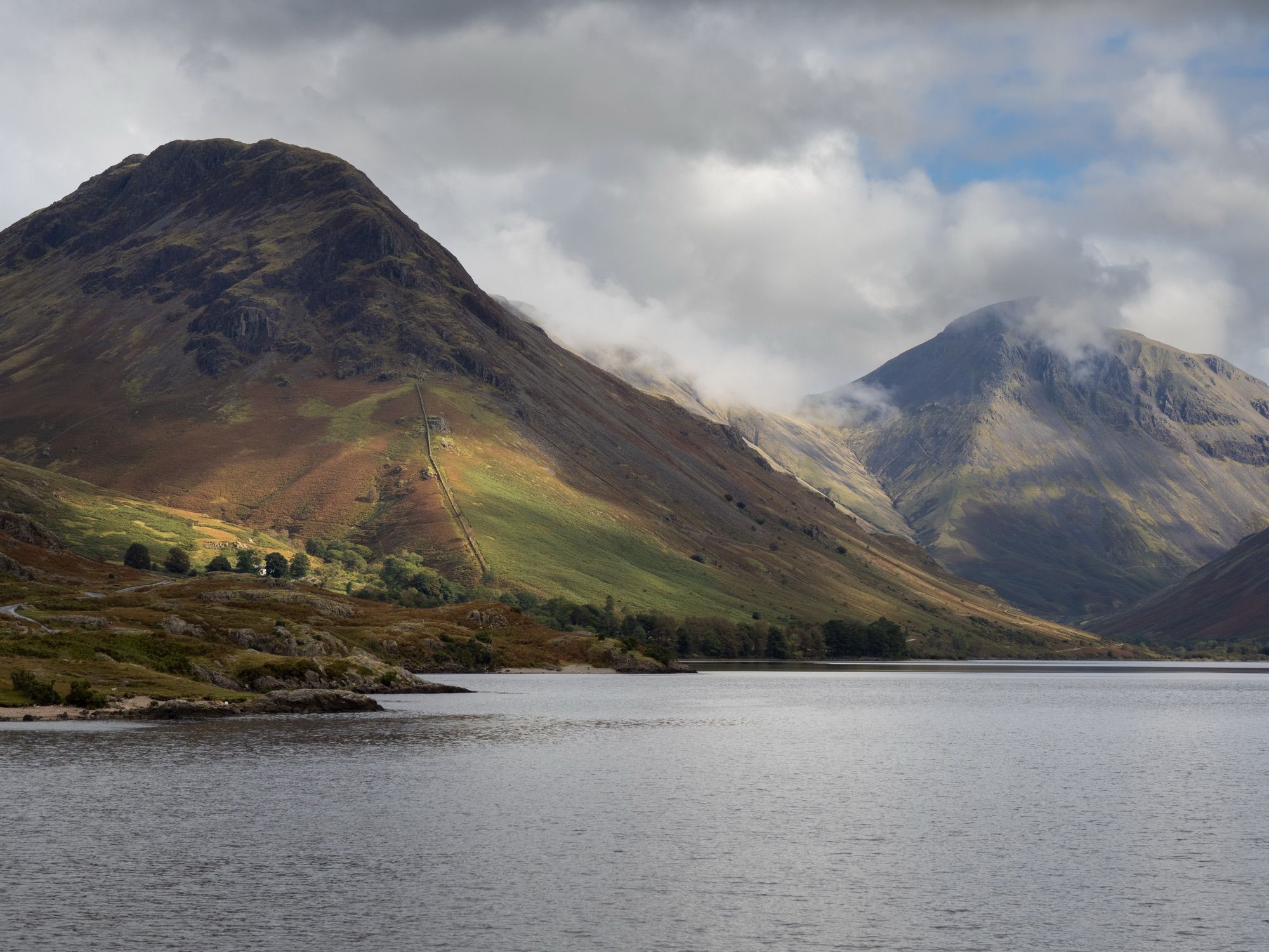 A photo of the top end of Wast Water showing two distinctive peaks Yewbarrow (left) and Great Gable (right). Great Gable is partly covered by mist.