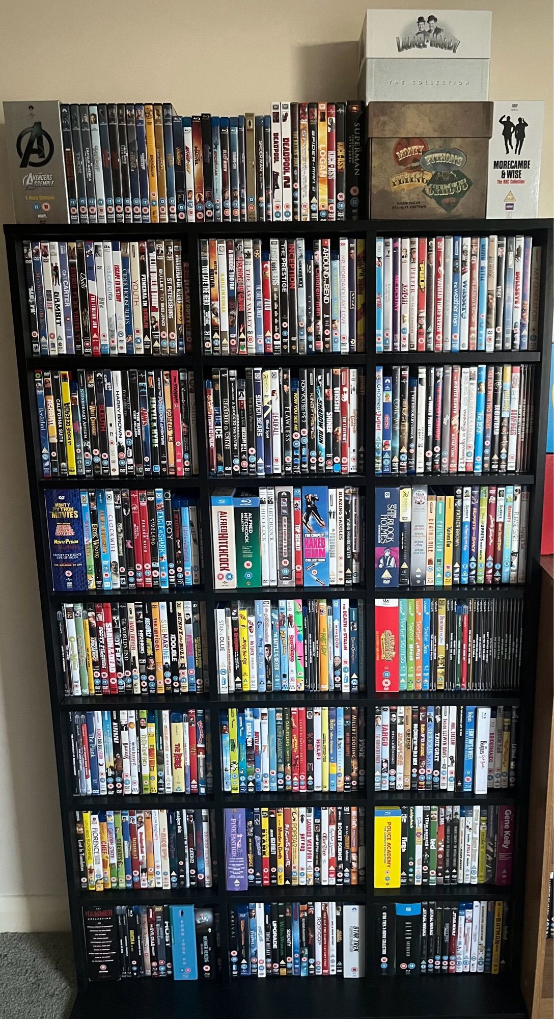 A big black shelving unit filled with DVDs and Blu-Rays of films with another load on the top of it.