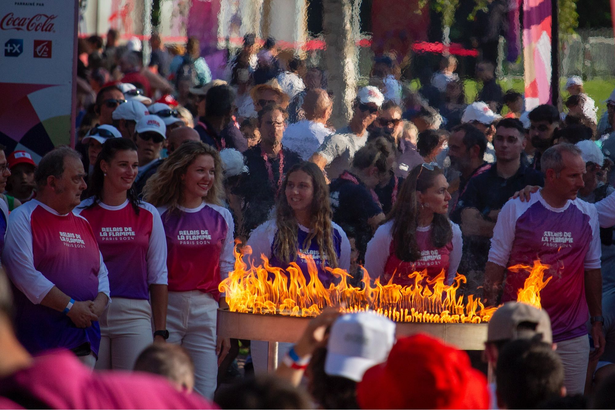 Le chaudron olympique allumé entouré de bénévoles